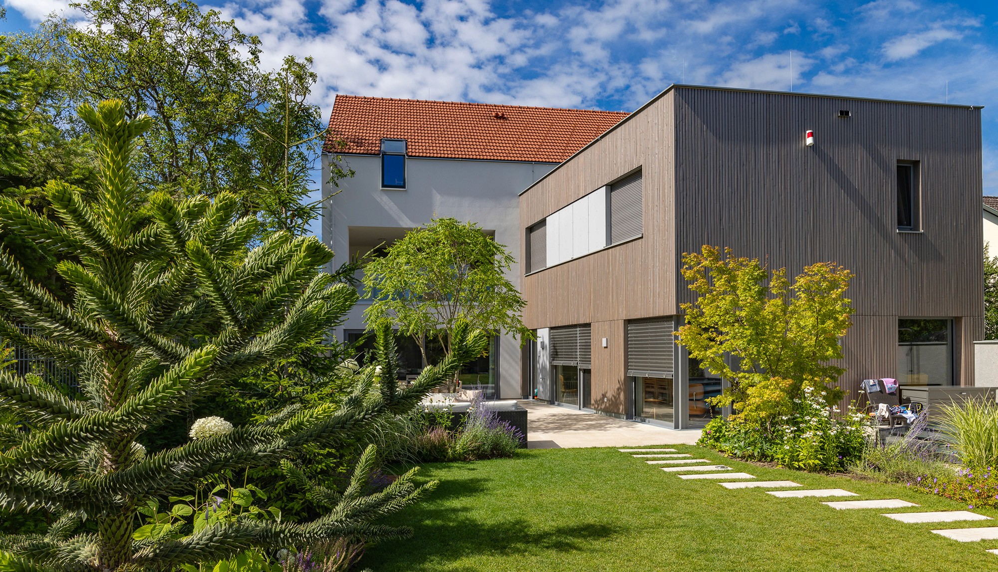 Moderner Privatgarten mit gepflegtem Rasen, Staudenbeeten und Naturstein-Trittplatten