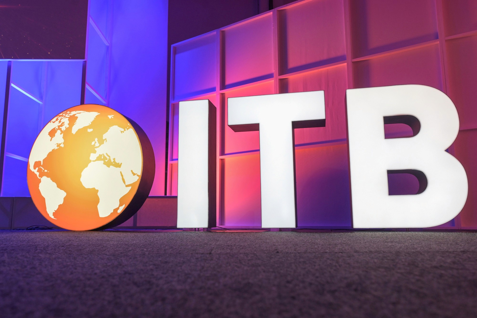 Letras monumentales de ITB junto a un globo terráqueo, con iluminación azul y magenta