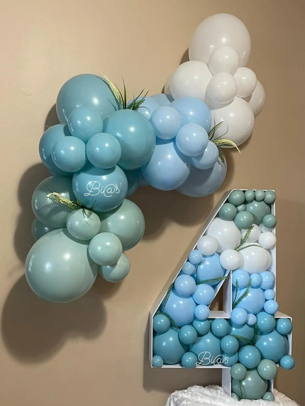 Blue and white balloon arrangement featuring a large number “4” structure filled with smaller balloons, creating a modern and eye-catching design. Perfect for birthdays and anniversaries. Susa’s Sweets & Balloons.