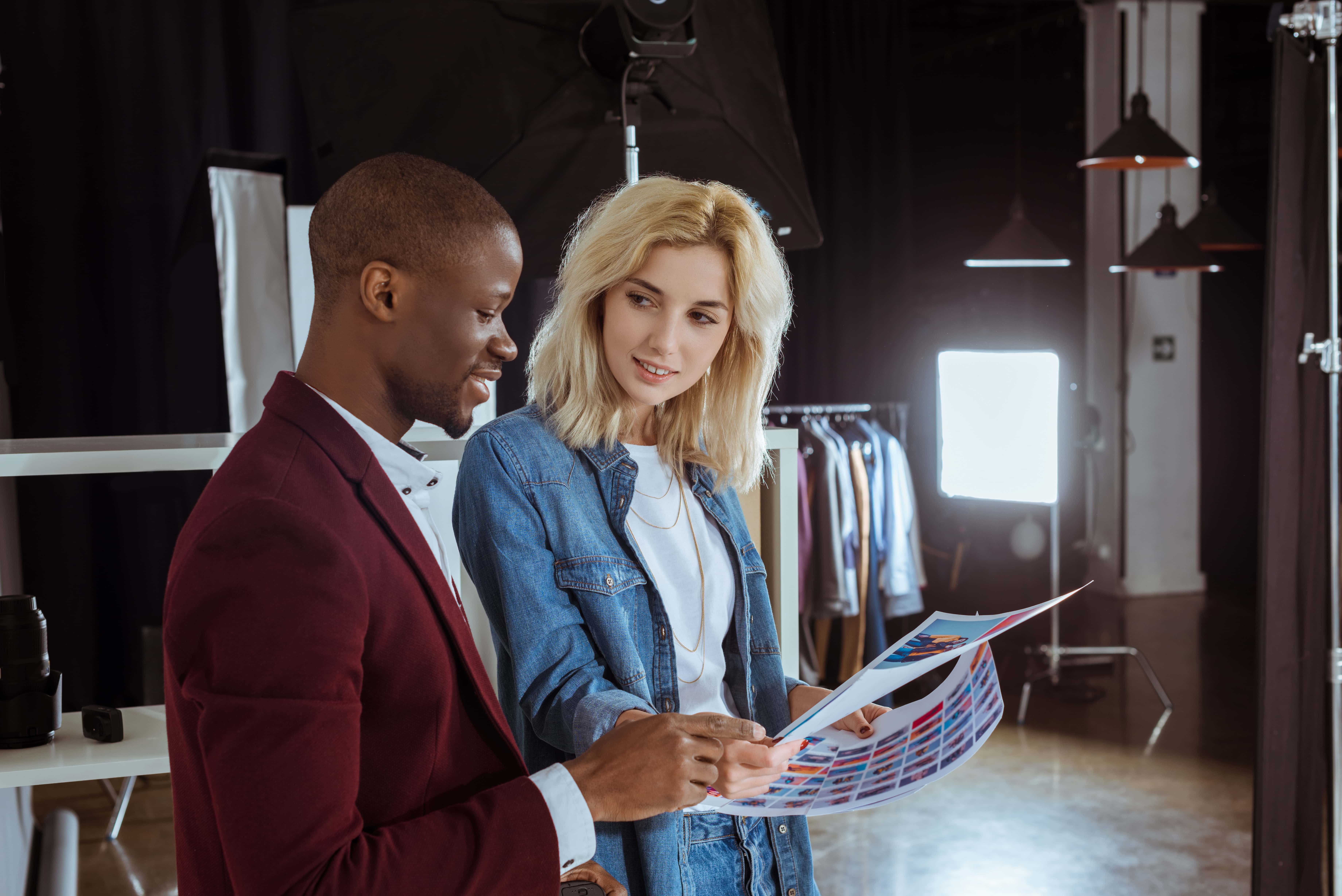 portrait of multiethnic photographers looking at portfolio together in studio