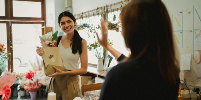 A Malaysian retail owner waving goodbye to a customer