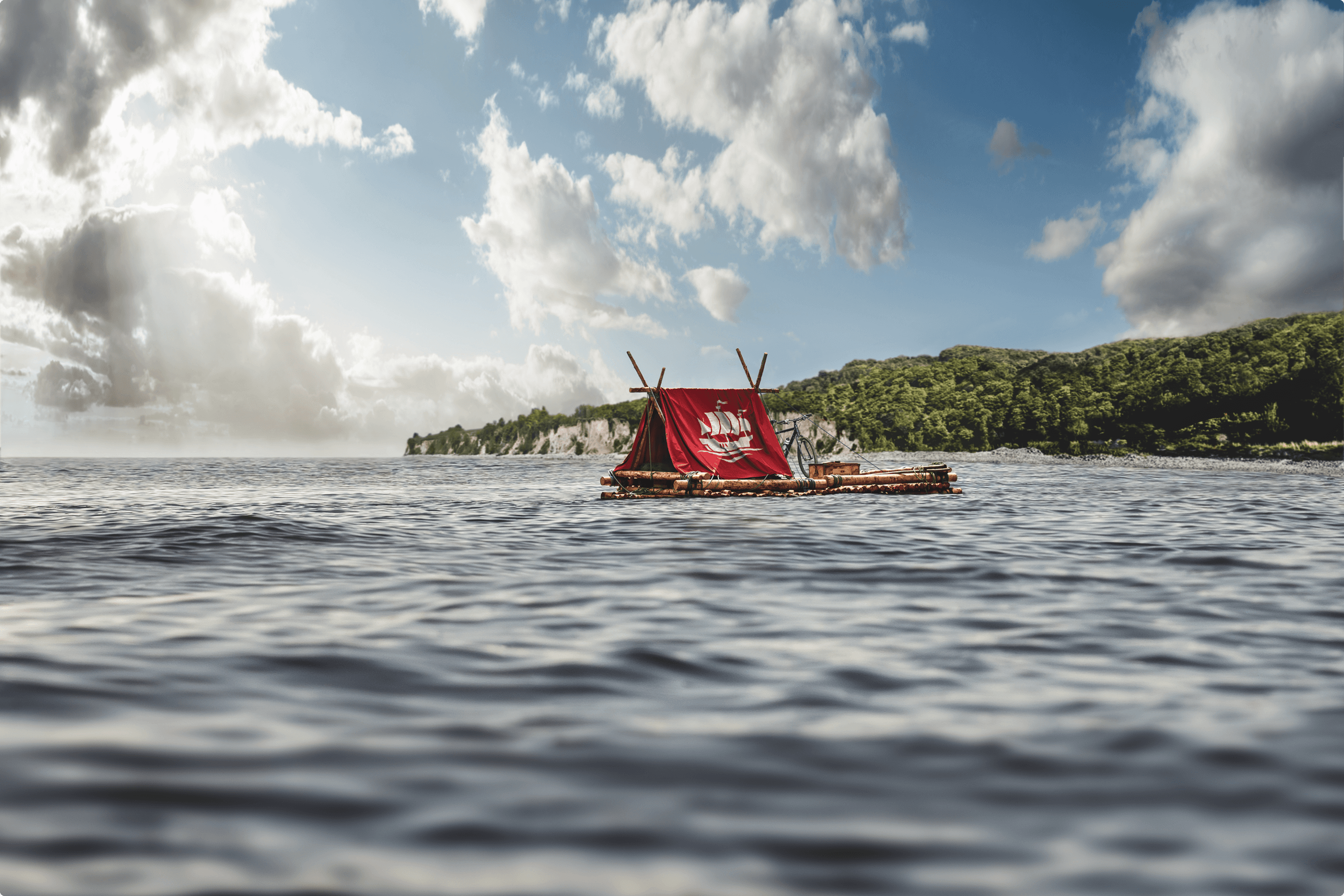 Raft with bamboo and red sail in the ocean.