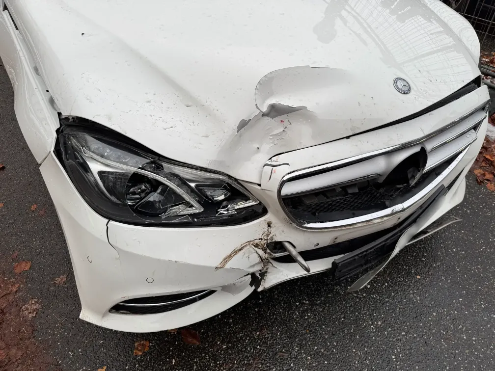 detail photo of a damaged front of an mercedes car.