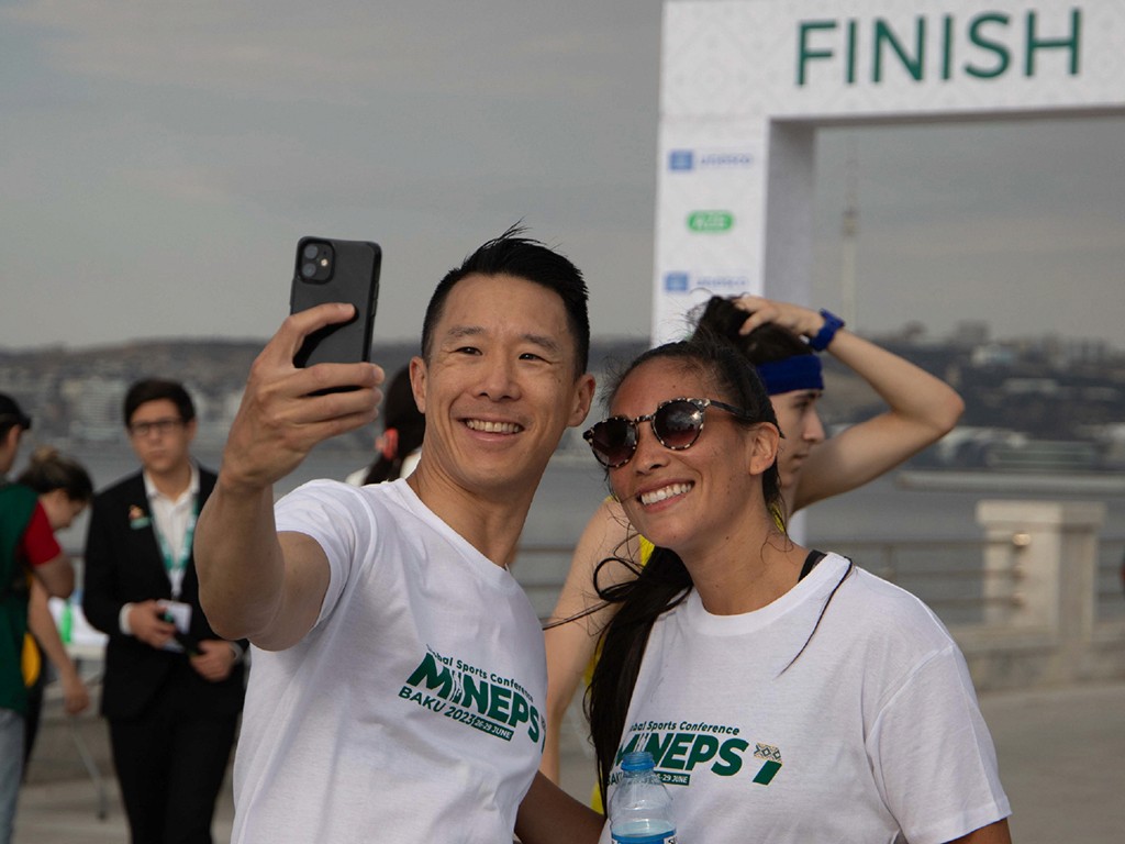 Close-up of a yellow tennis ball sitting on a green court, positioned near the white center line.