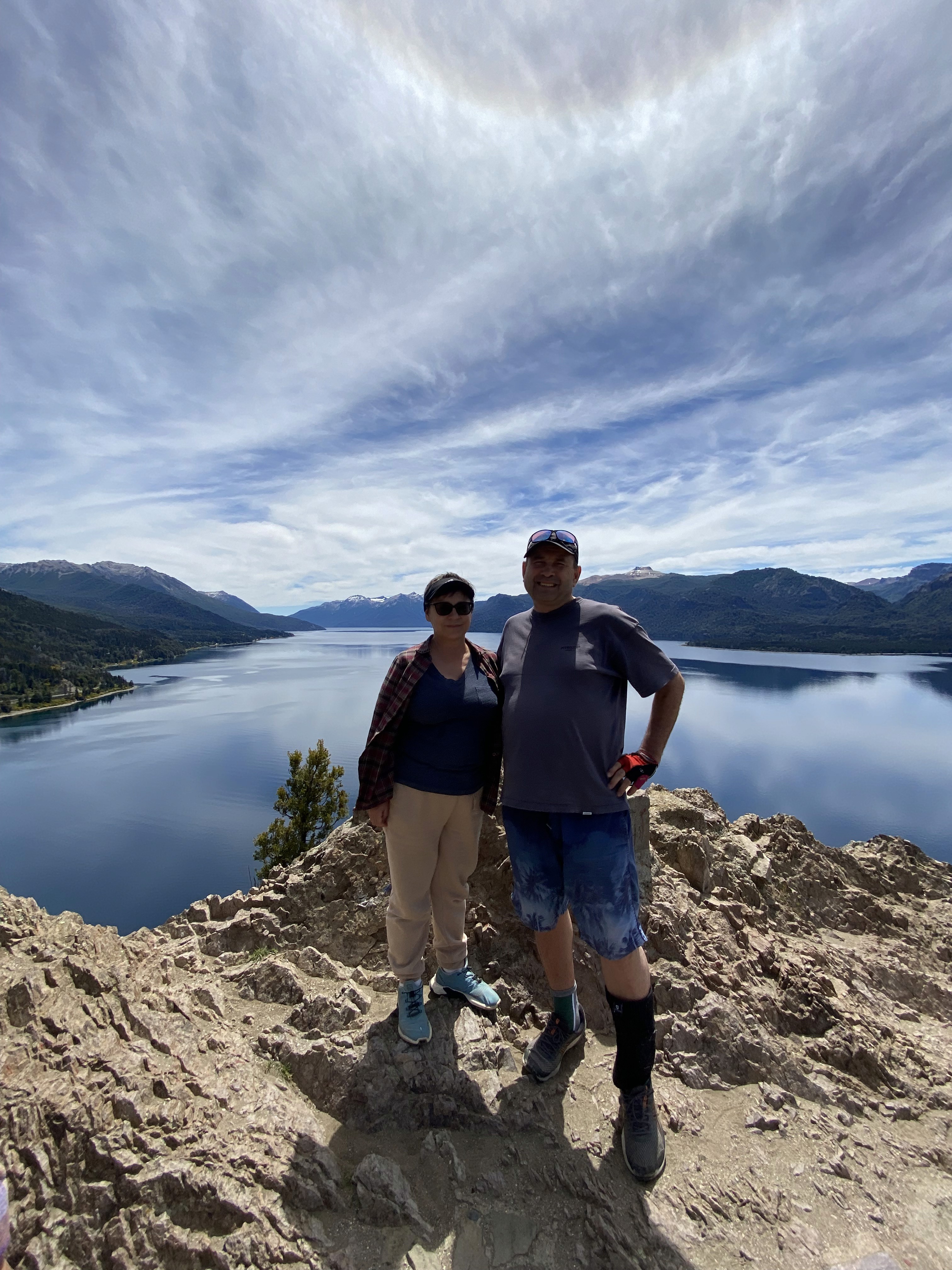 Mujer sentada sobre un tronco frente a una cascada doble en un bosque frondoso de Argentina.