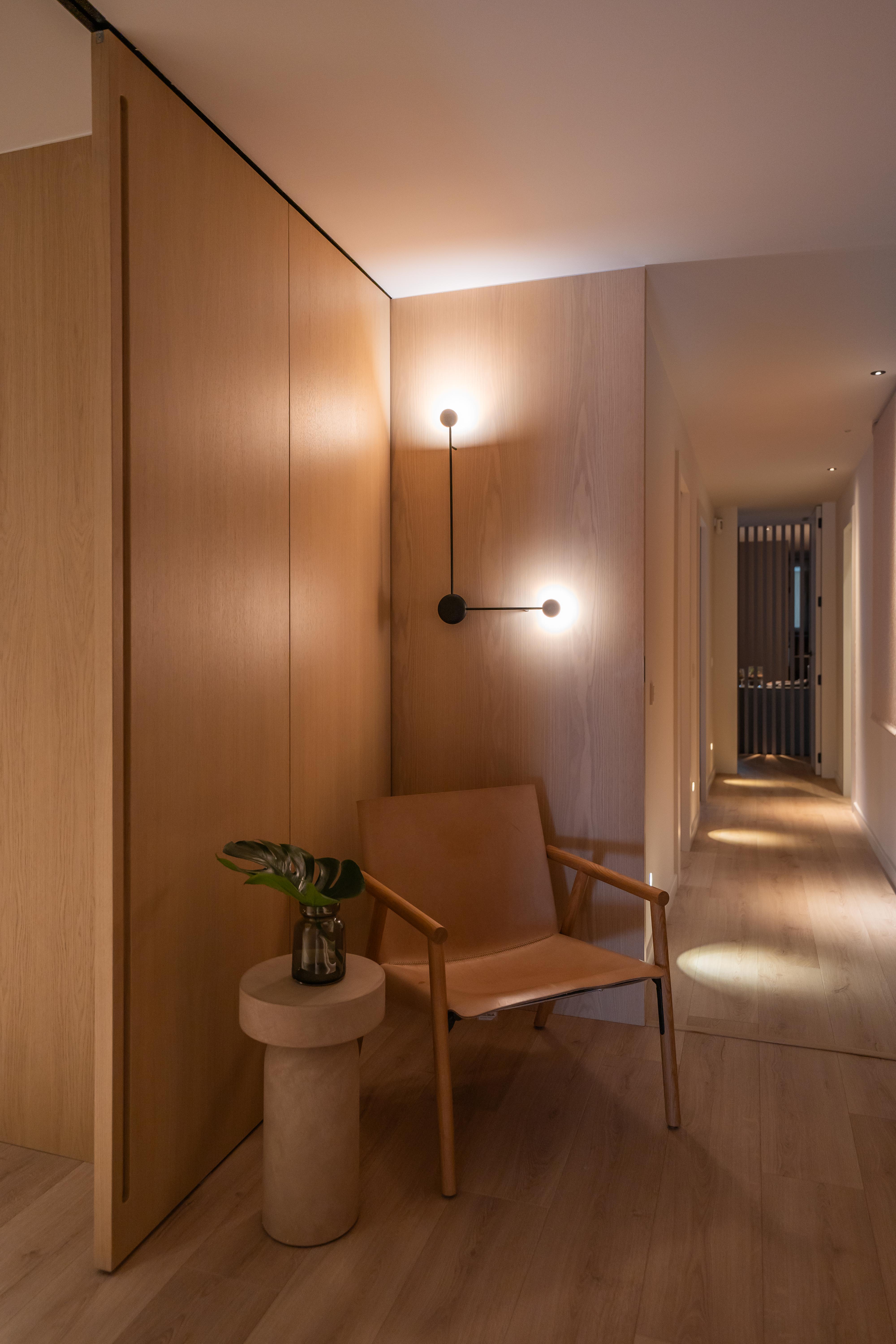 Pasillo con paredes de madera clara y silla con lámparas de pared