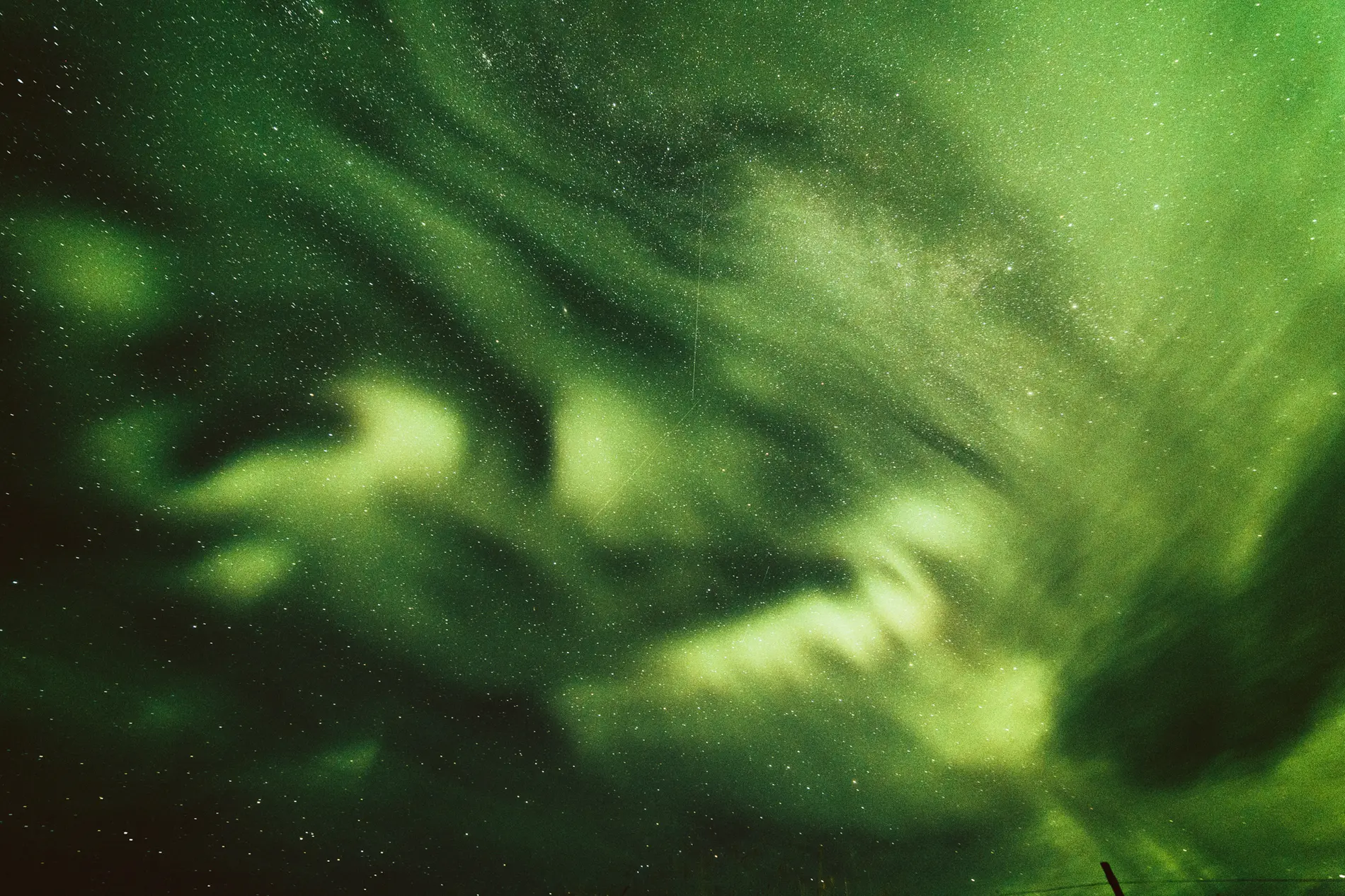 Green aurora curling across a star-filled night sky