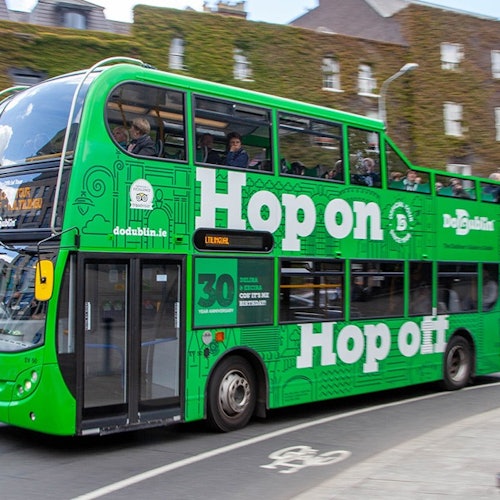 Green bus travelling in front of old buildings