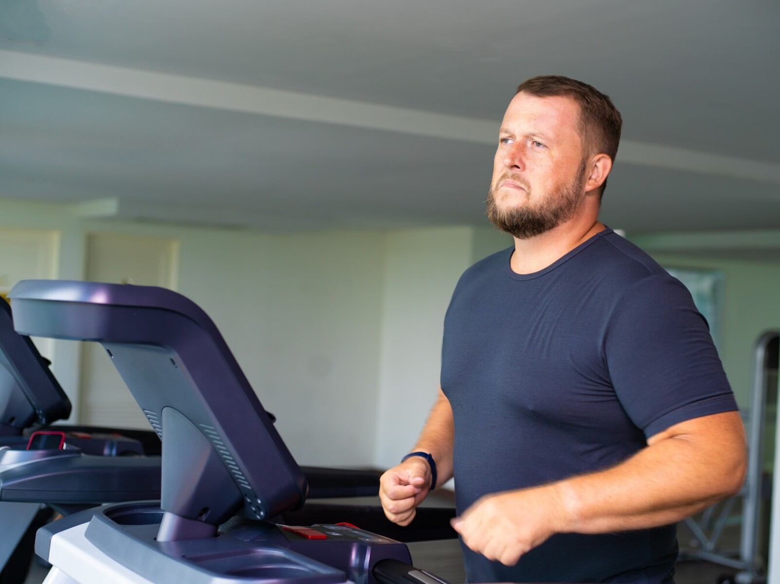 plus-sized man hitting a plateau and struggling to lose weight walking on a treadmill in the gym