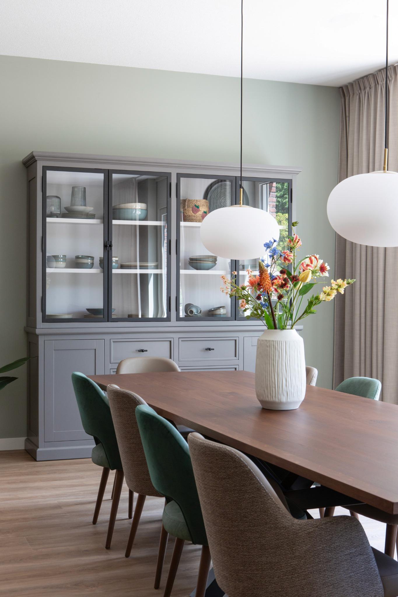 eettafel met grijze servieskast en bollampen glas