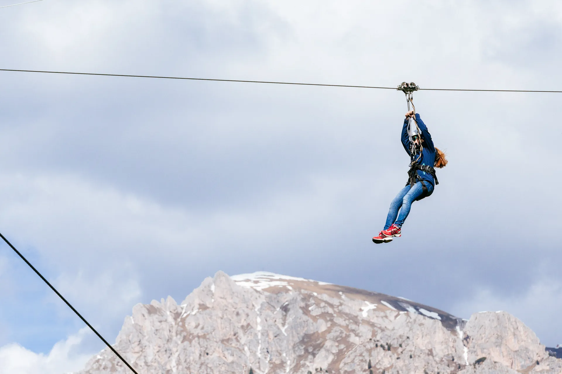 Volo sulla zipline con cime dolomitiche e cielo azzurro