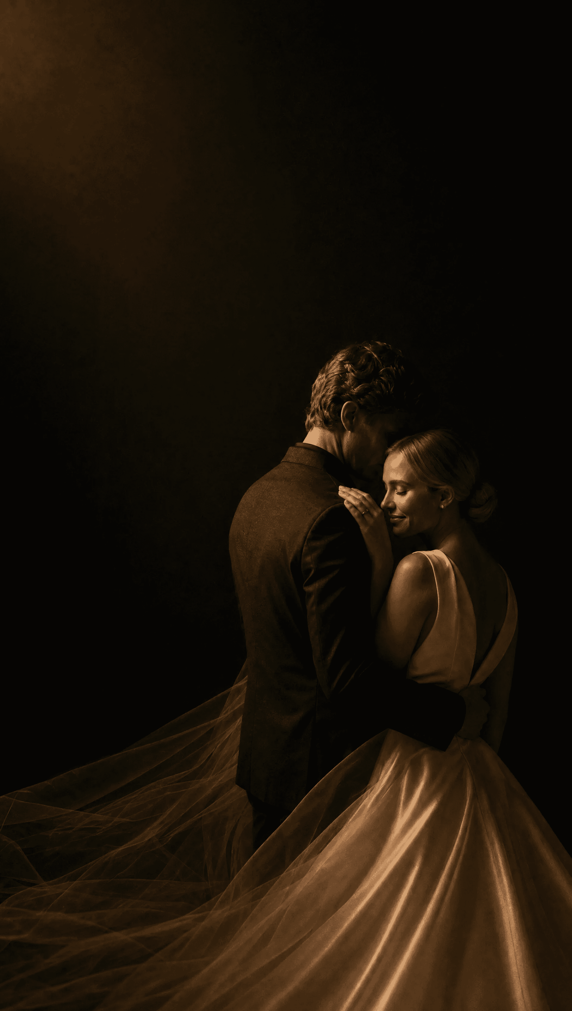 A couple in modern wedding attire embracing in candlelight, her veil flowing into the dark