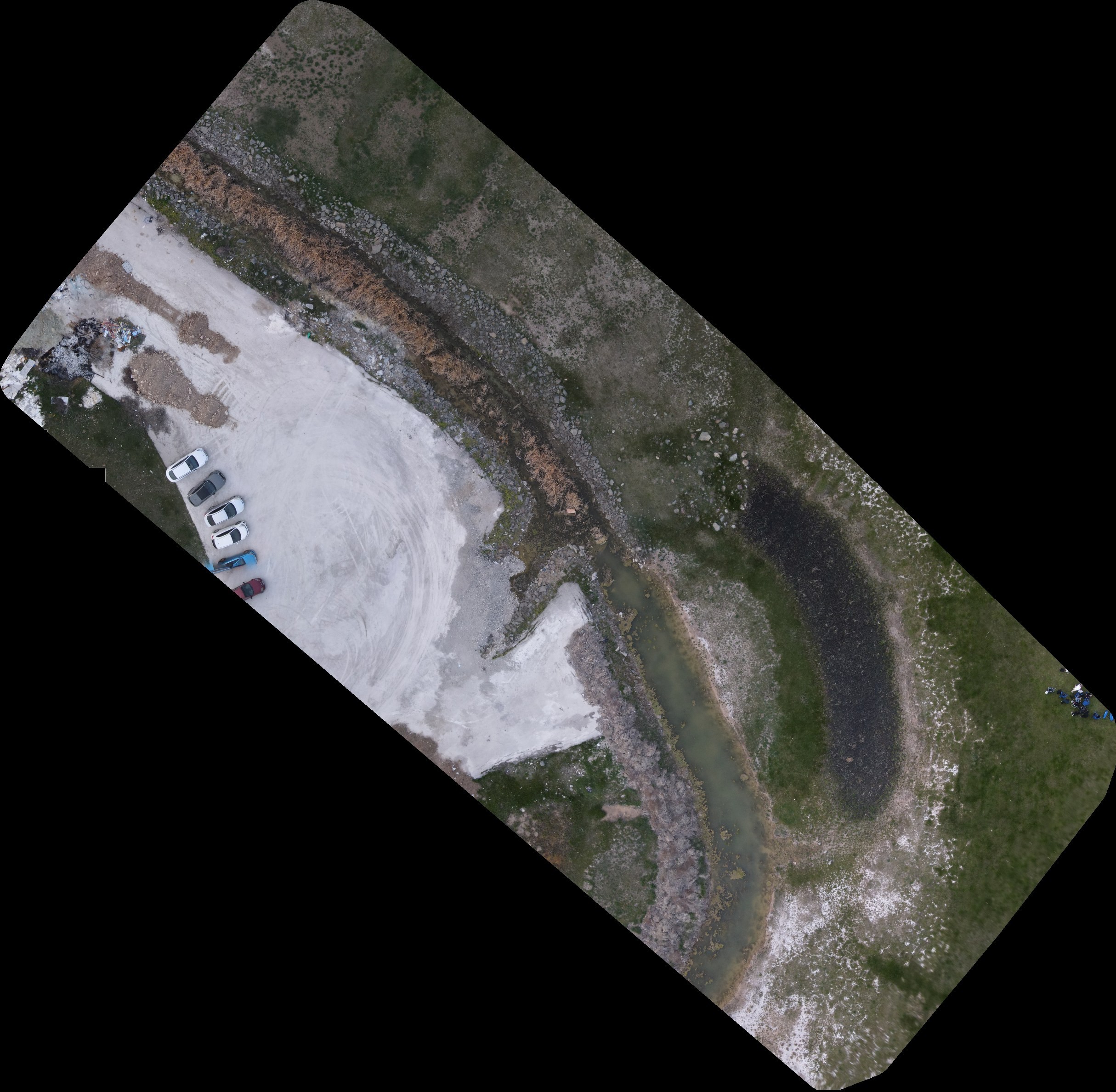 Second stitching test, over the flight-test field. The scene is natural ground cover — grass, gravel, bare soil, a graded lot and a watercourse running through the frame — rather than the built model of Figure 5. This run also used no coordinate data.