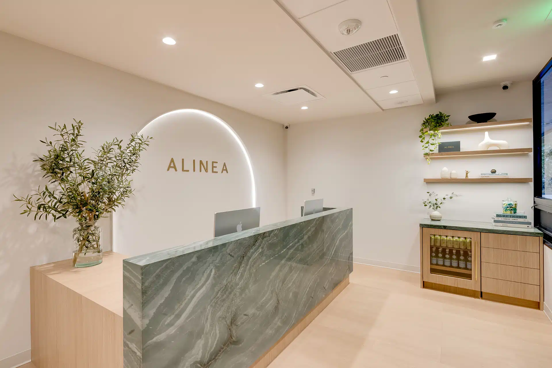 Alinea Orthodontics reception desk featuring illuminated arch wall and gold logo signage in a modern dental clinic.