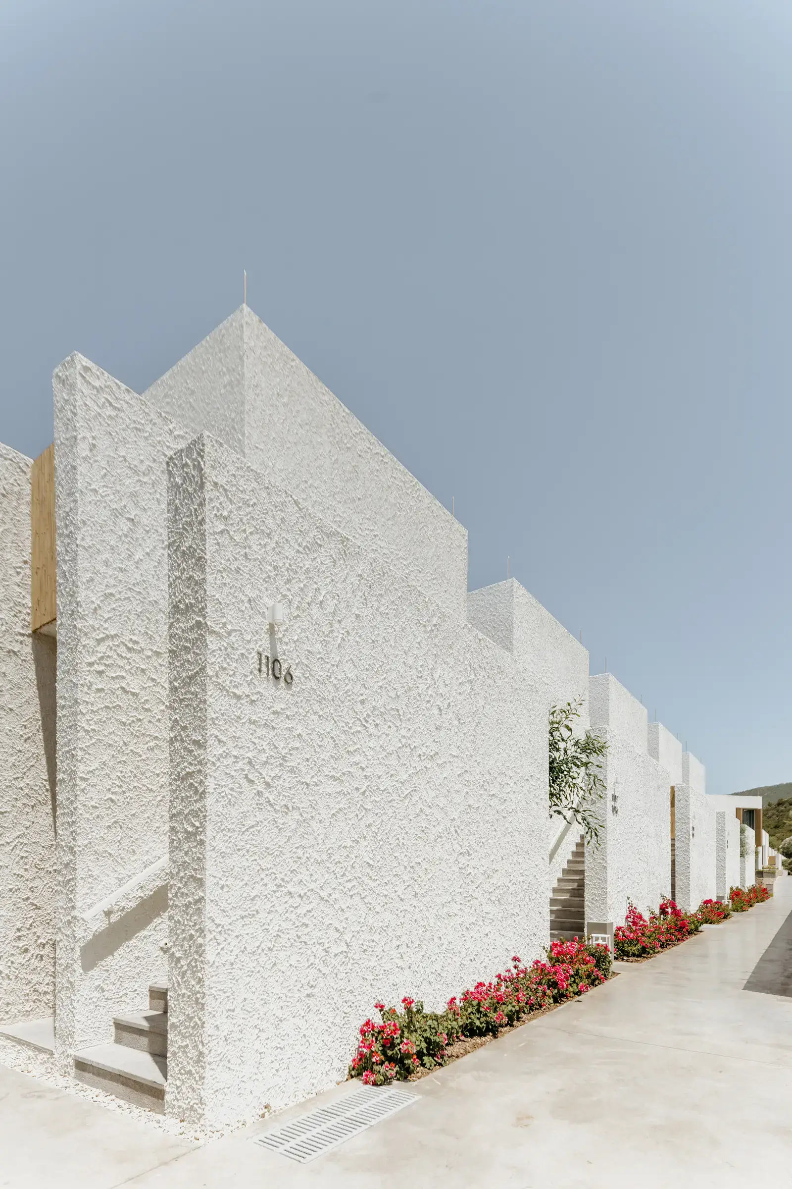 Stepped white walls and a flower-lined path