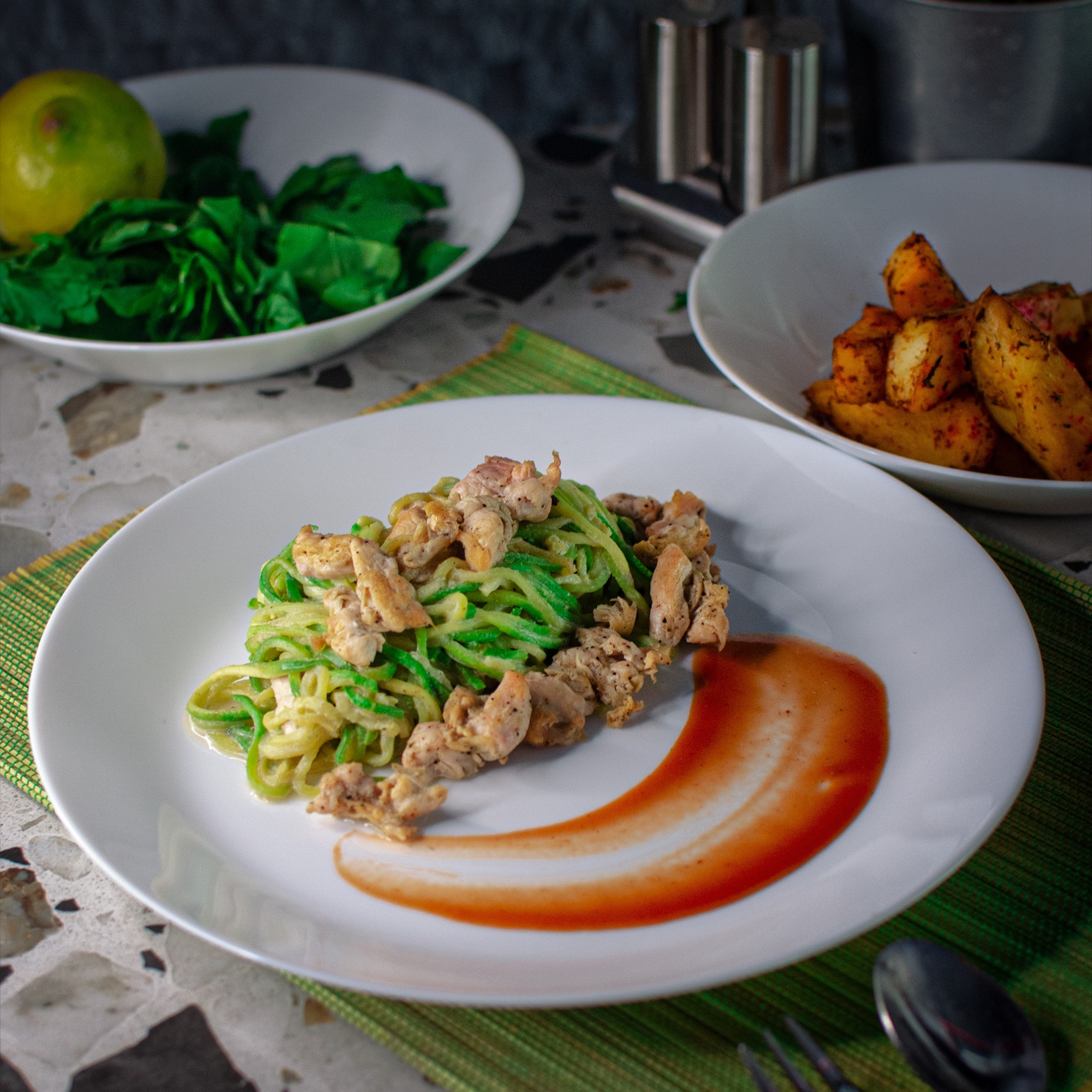 A close-up of a wok or large pan filled with golden noodles and vegetables, with a cook's hands adding more noodles, capturing steam and warm sunlight in a busy, rustic outdoor or market setting.