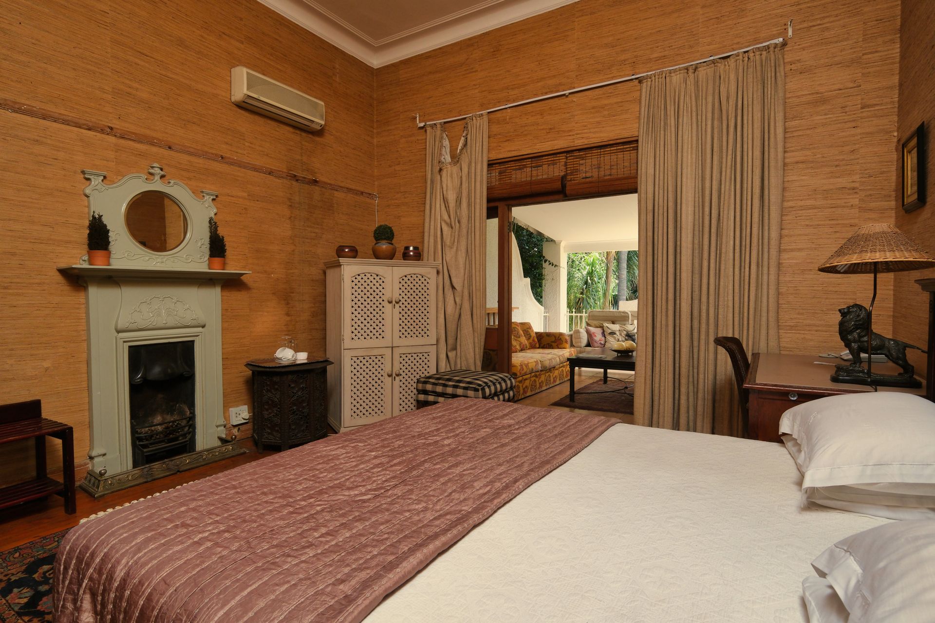 Classic guest bedroom with a fireplace, king-size bed and doors opening to a sitting area