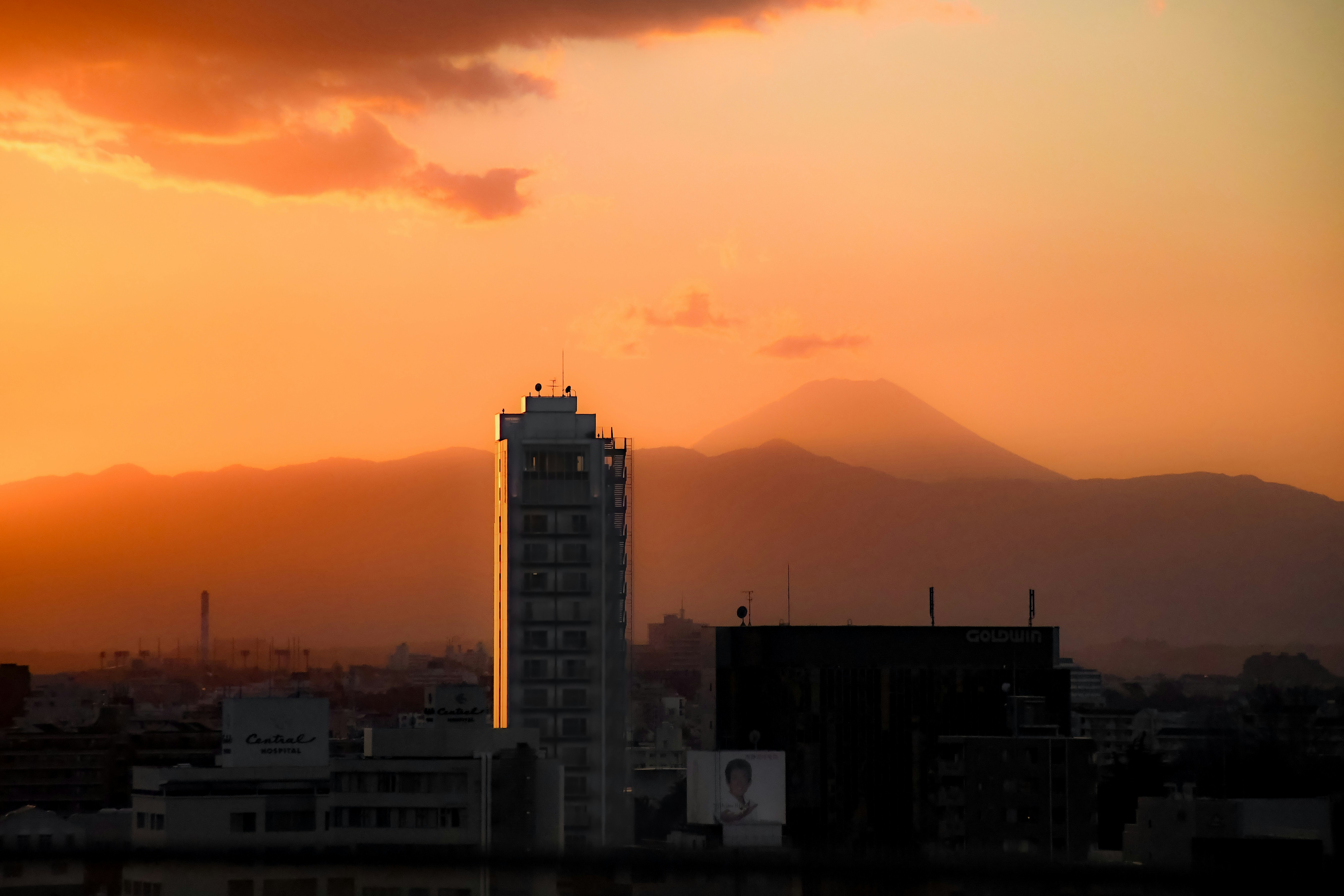 Tall central building set against a mountainous backdrop at sunset