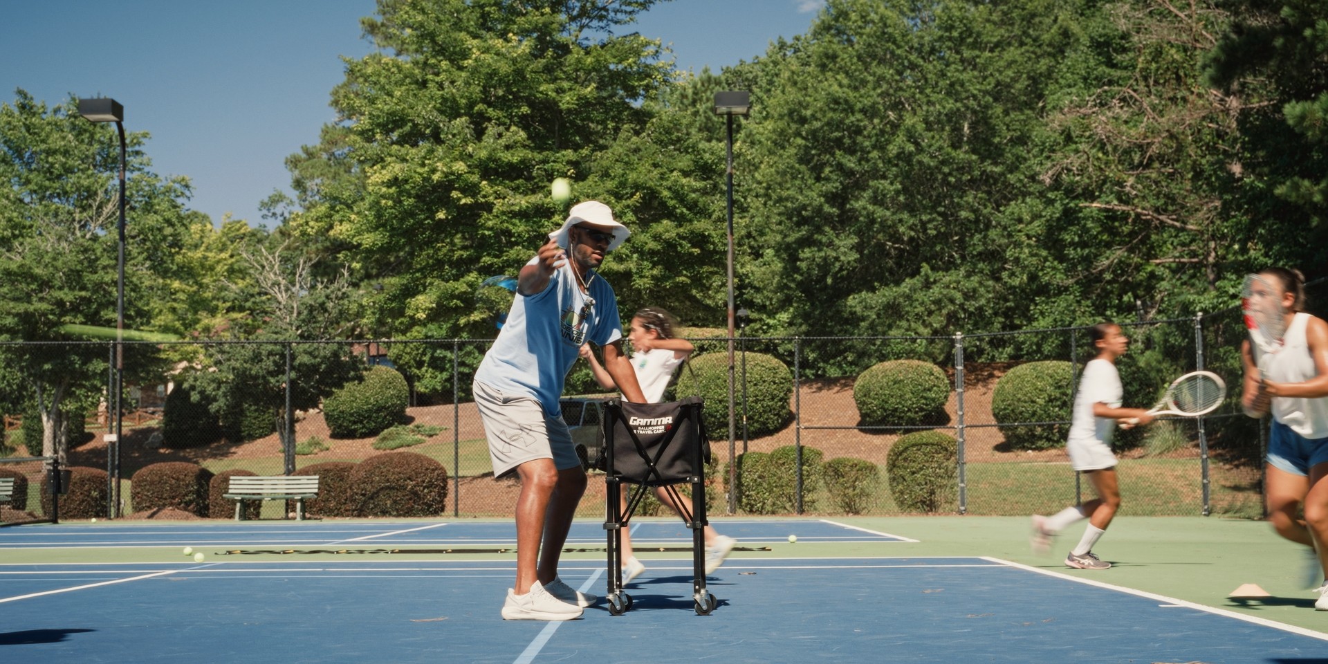 Entraîneur lançant une balle pendant un entraînement de tennis en plein air