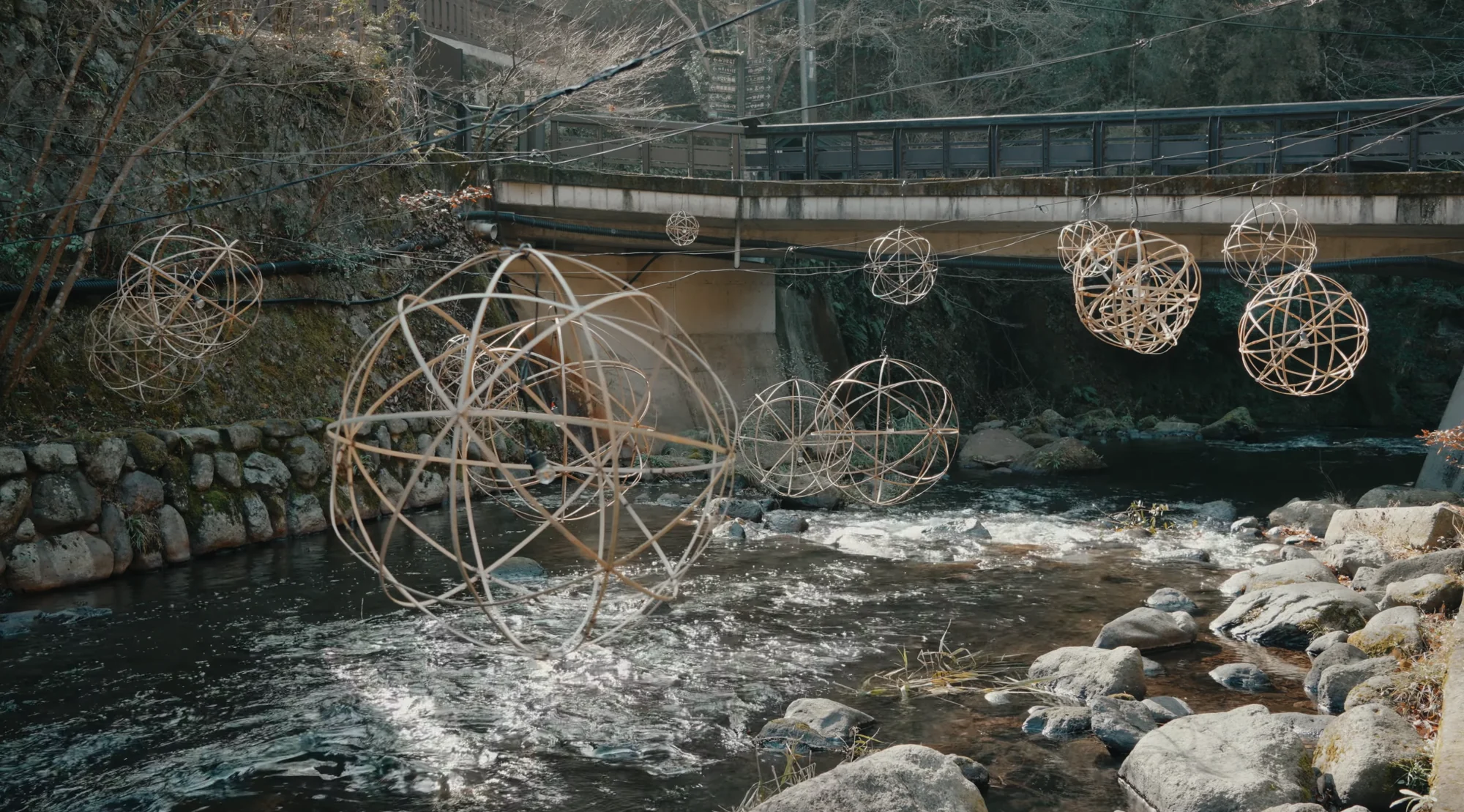 Large woven bamboo lantern spheres standing in the running river in daylight