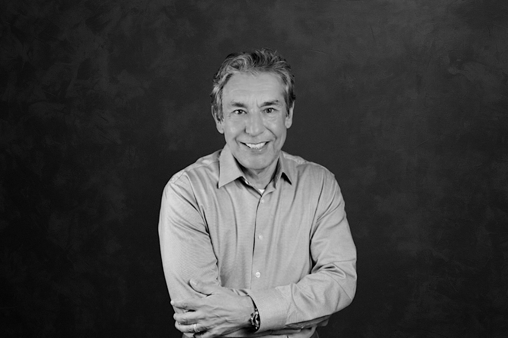 Portrait of a woman with straight long hair, in a dark t-shirt, set against a neutral backdrop.
