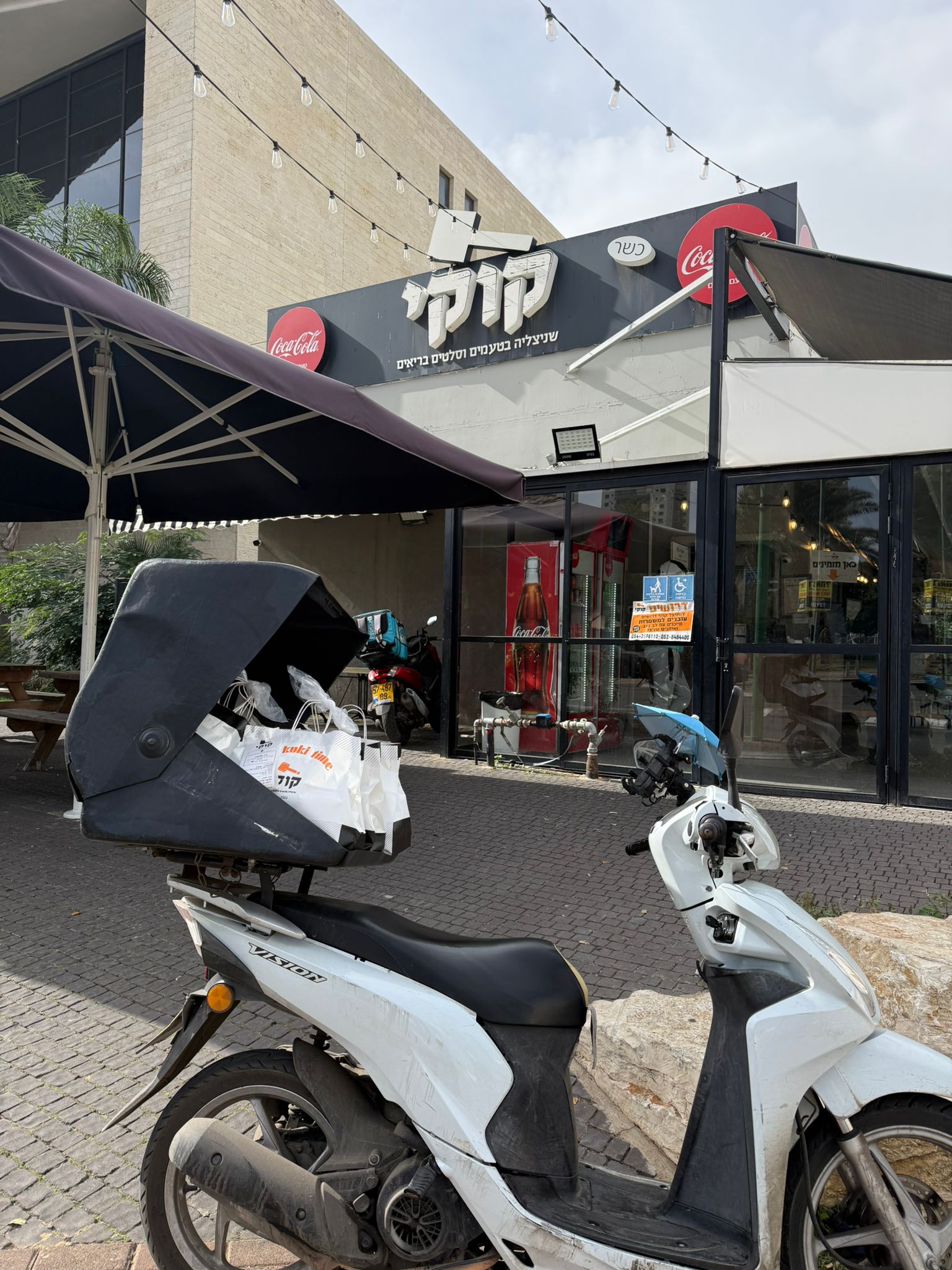 שקיות משלוח מונחות בקופסת אופנוע מחוץ למסעדה.