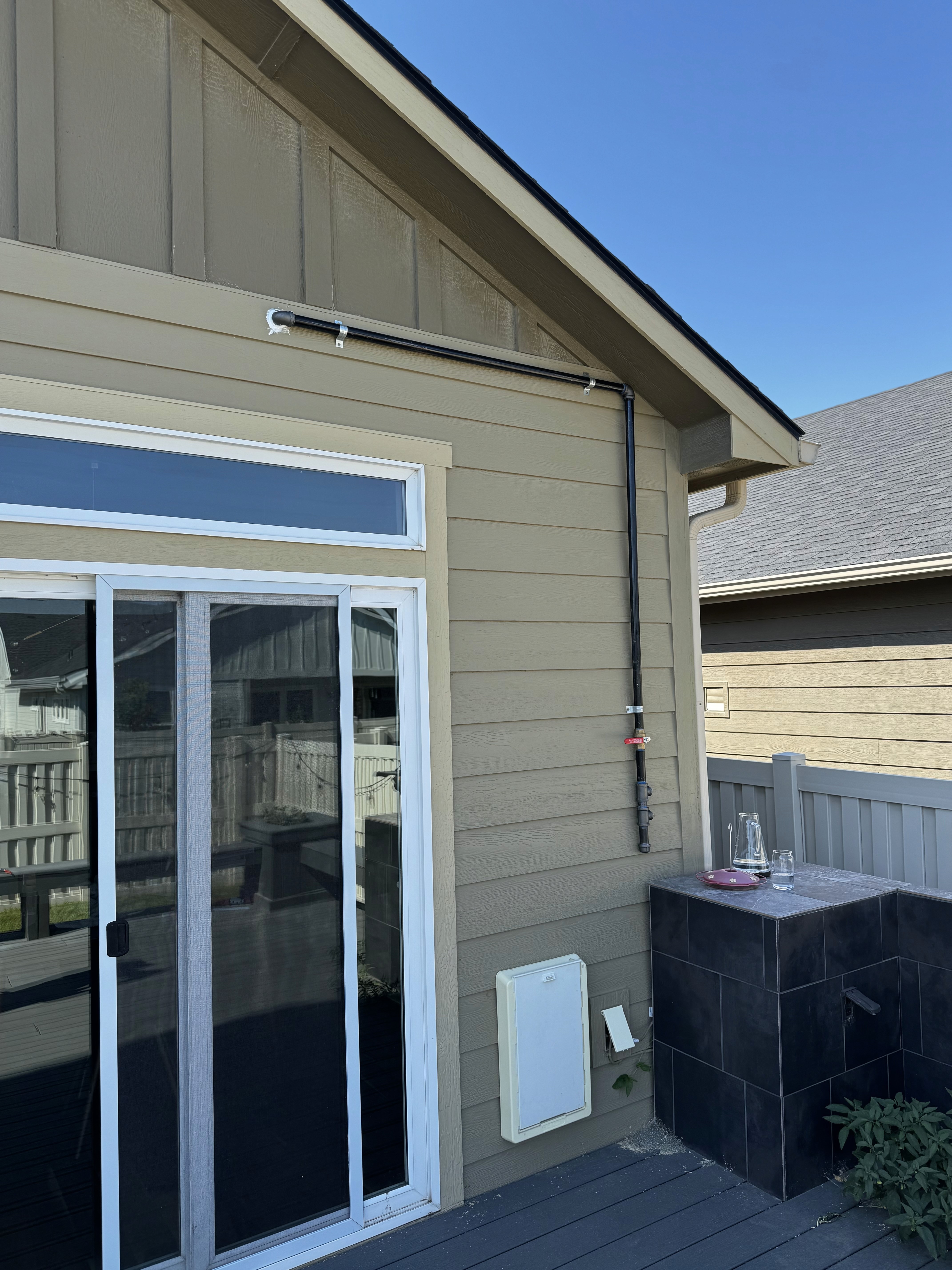 A smiling young man with crossed arms, wearing a plaid shirt and white t-shirt, poses against a dark background.
