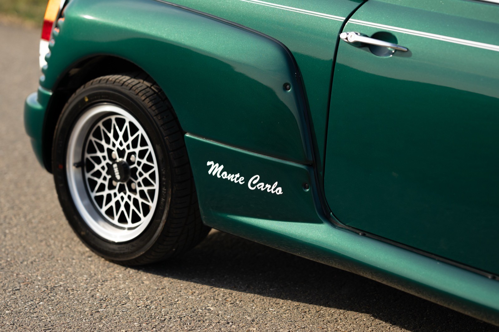 Close-up of a green car's wheel and fender, showcasing sleek design and intricate alloy wheel detail.