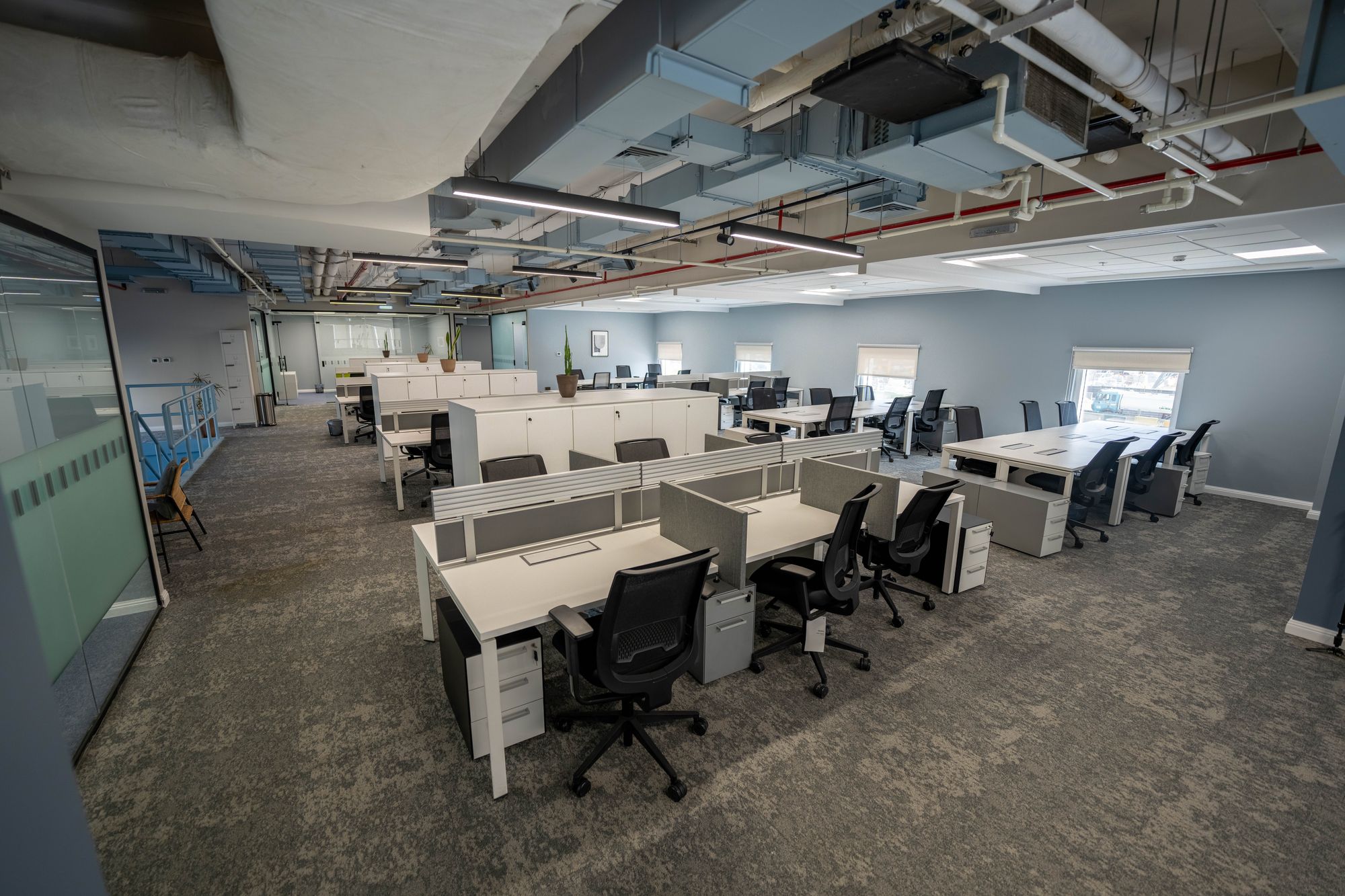 طابق مفتوح واسع بصفوف من محطات العمل لفريق ينمو في ديوم HQ ببرج النخلة، الدور الأرضي