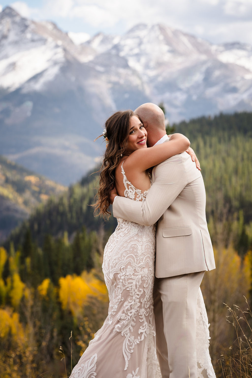 Close-up of a bride smiling warmly at the camera while embracing her groom during their mountain elopement. This candid moment showcases the expertise of a Silverton Colorado wedding photographer in capturing genuine emotion.