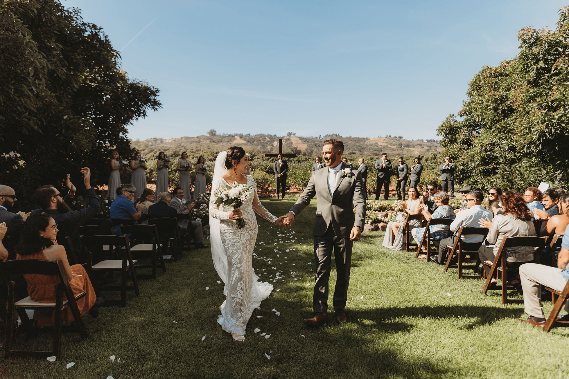 Bride and groom walking down the aisle with guests cheering