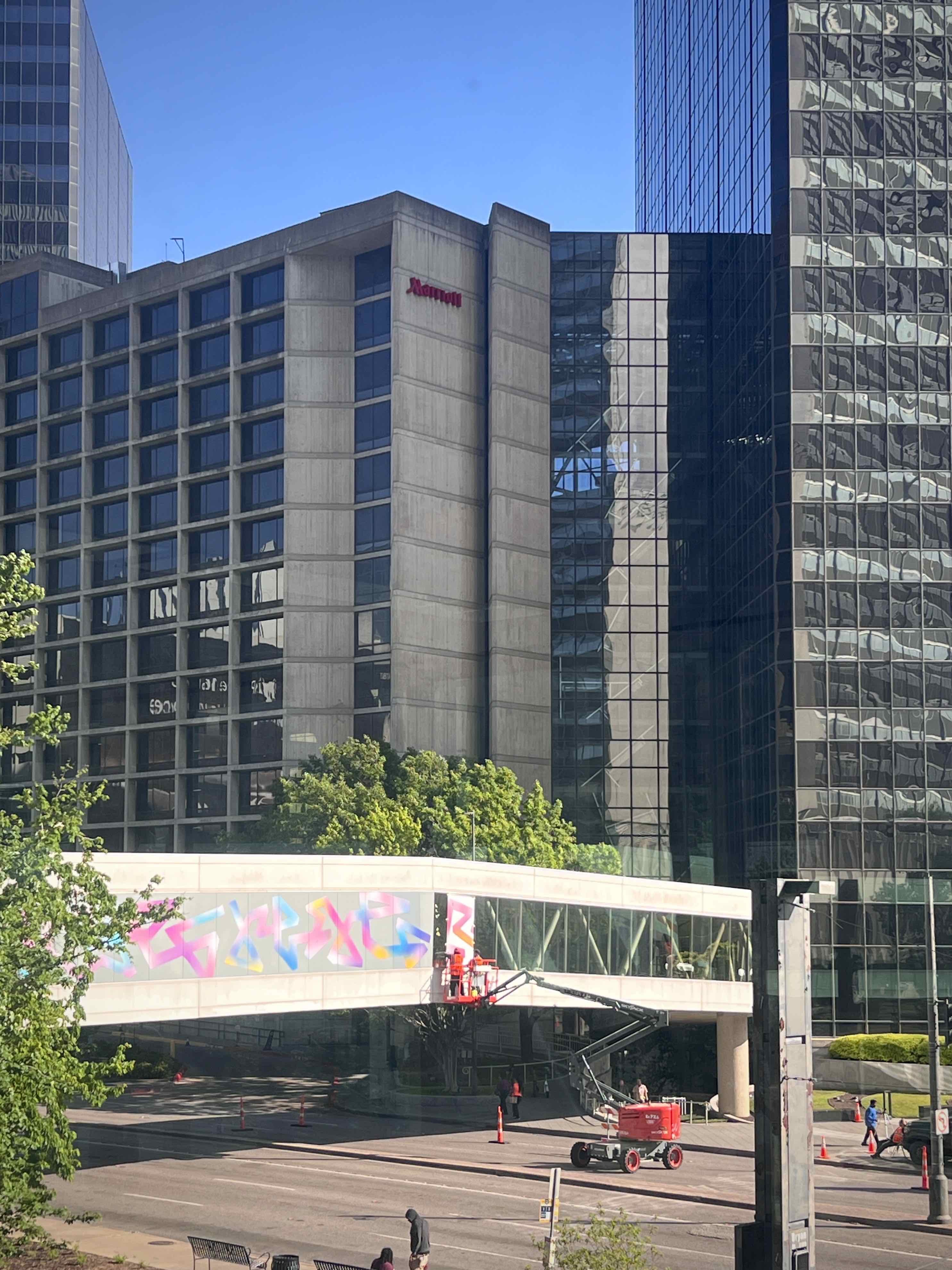 A modern urban scene featuring tall glass buildings and a clear blue sky.