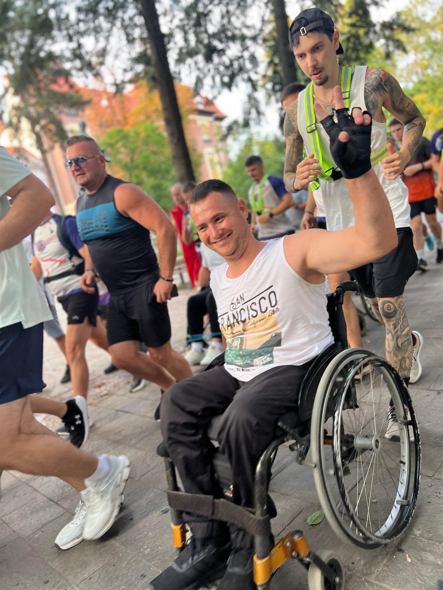 Participant în scaun rulant ridică brațul în timpul alergării incluzive din Oradea, alături de alergătorii comunității.