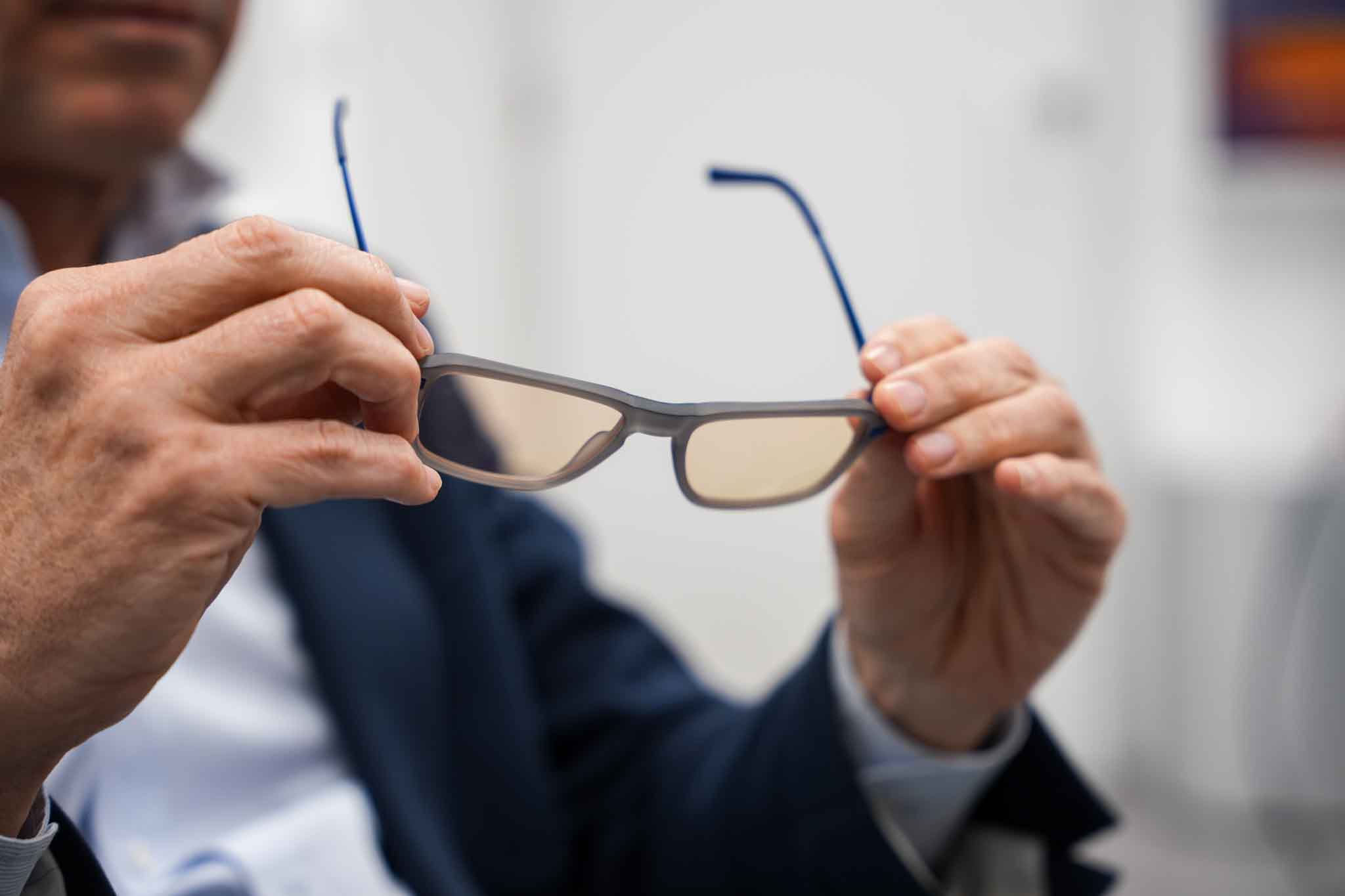Determined woman walking on an outdoor running track, wearing a white cropped top with mesh sleeves and black track pants on a cloudy day.
