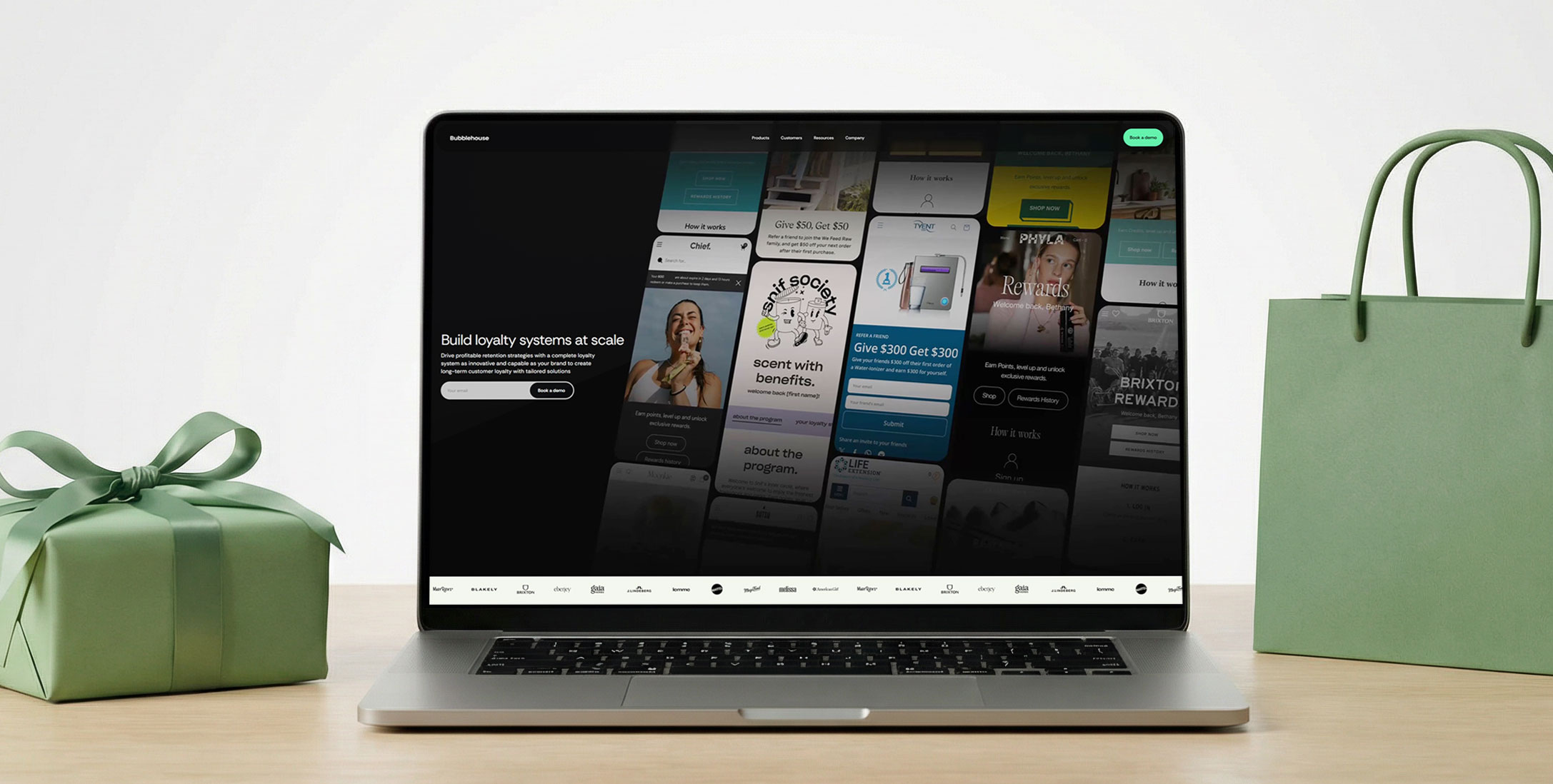 Laptop displaying a website design alongside a gift and shopping bag on a wooden desk.