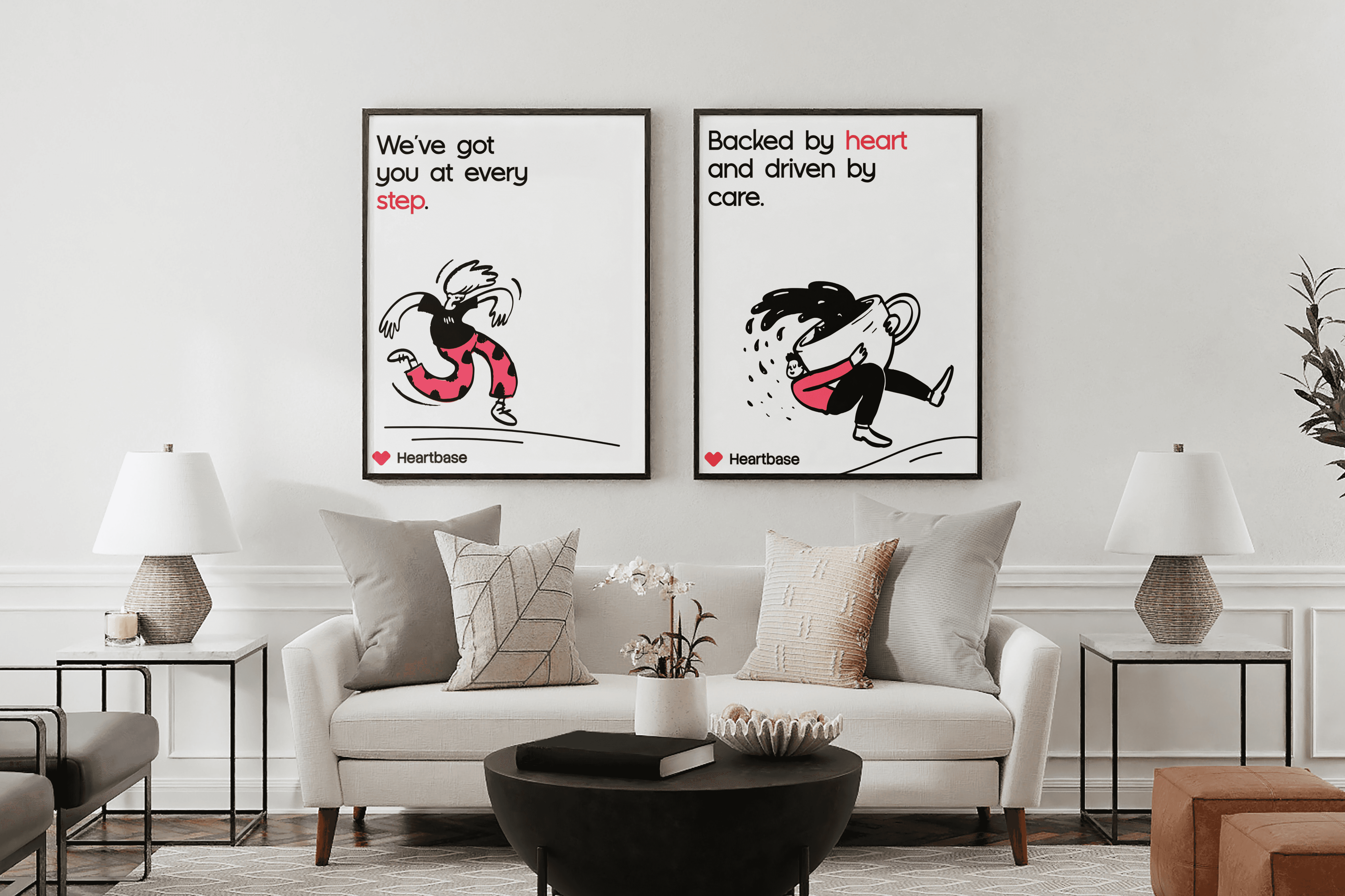 A modern living room features two framed minimalist posters on a white wall, showcasing playful, black-and-white cartoon figures with red accents, above a white sofa with various neutral-toned cushions and a chic coffee table.