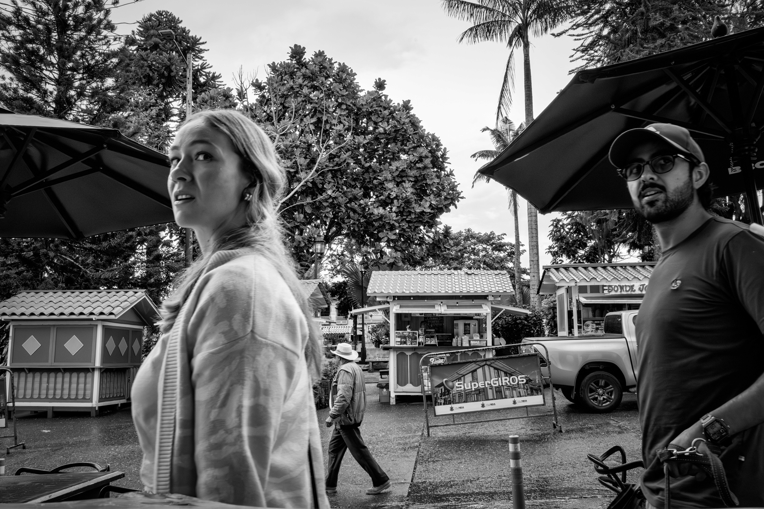 Rainy street scene with people passing by a bar window.