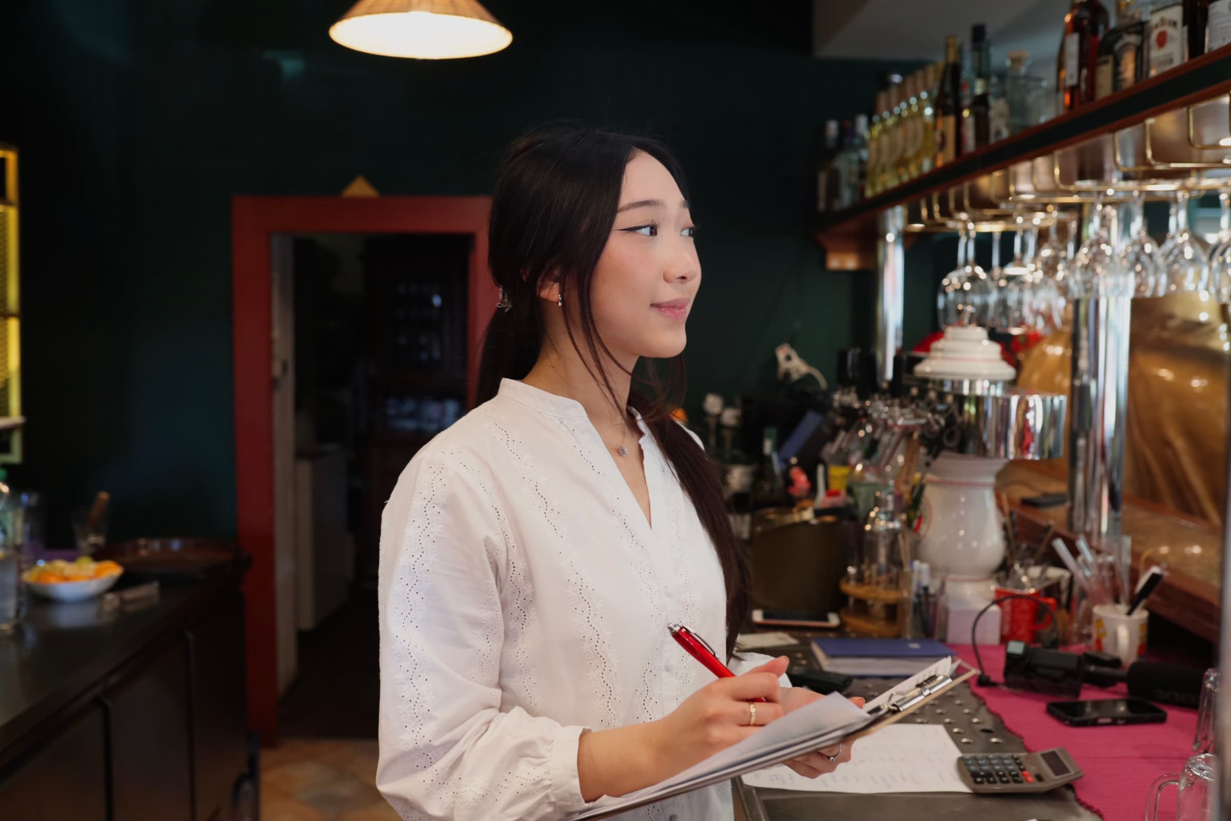 Asiatischer Koch in schwarzer Kochjacke in Restaurantküche stehend.