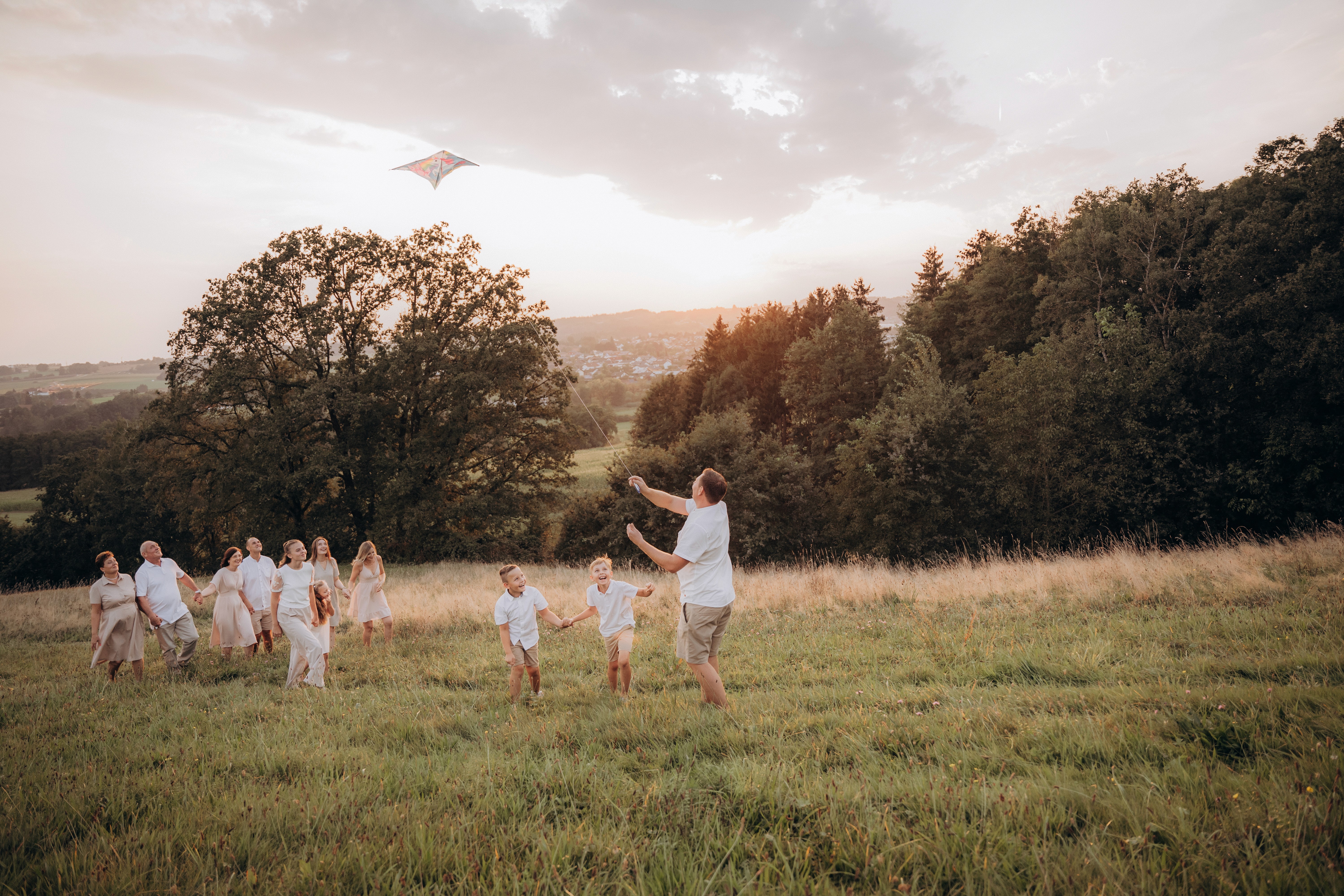 Natürliche Familienfotografie Outdoor in Bogen – Großfamilie läuft gemeinsam über eine Wiese bei Sonnenuntergang.
