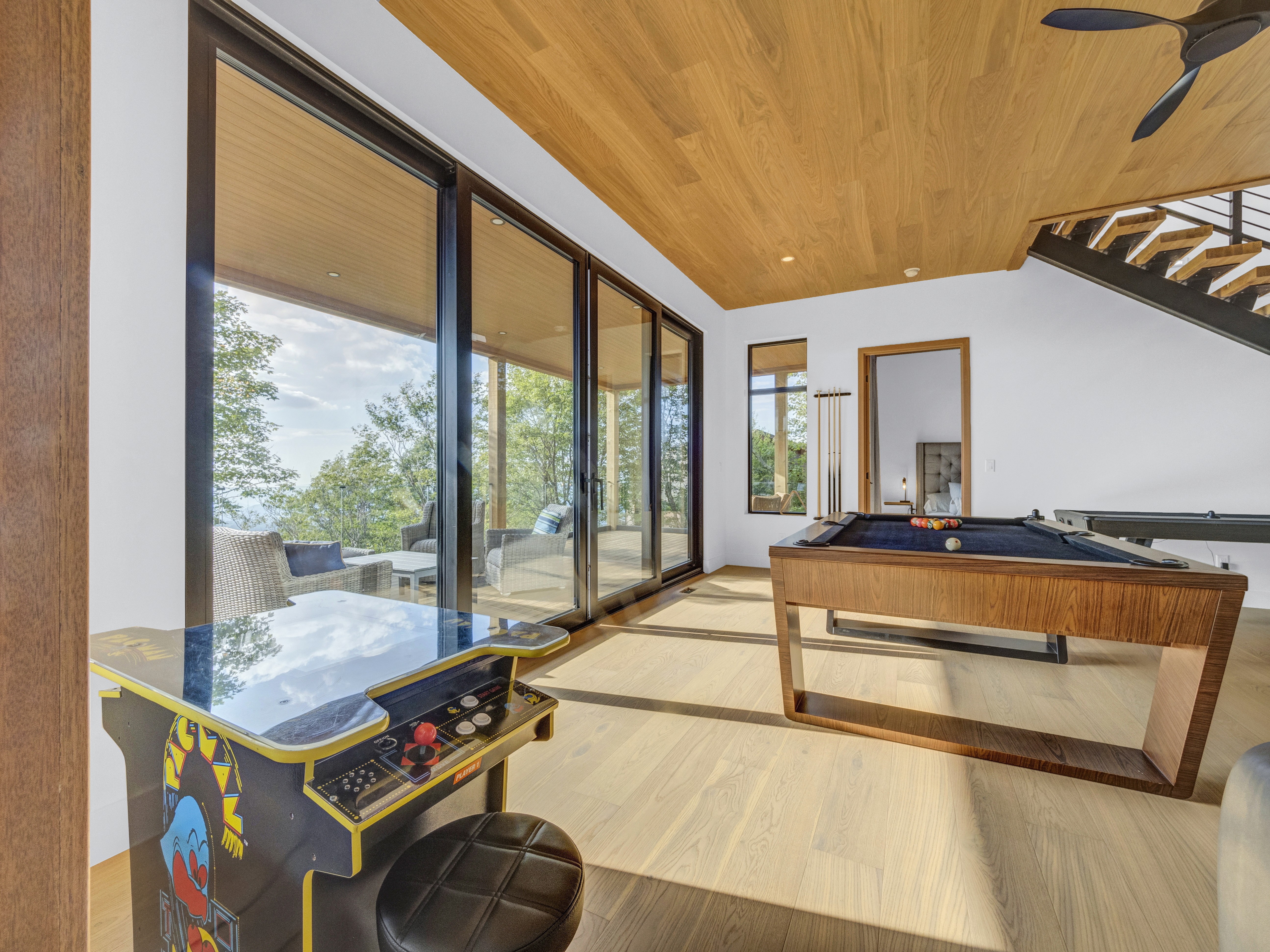 Dramatic aerial view of a multi-level luxury cabin at sunset, showing lit decks, a fire pit, and expansive glass walls