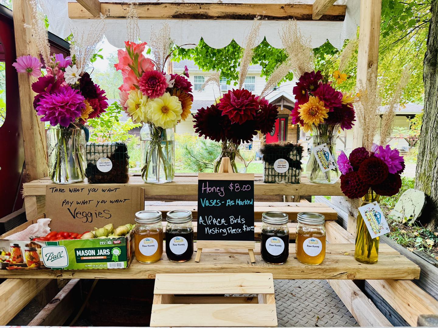 A stand selling flowers, honey, and veggies