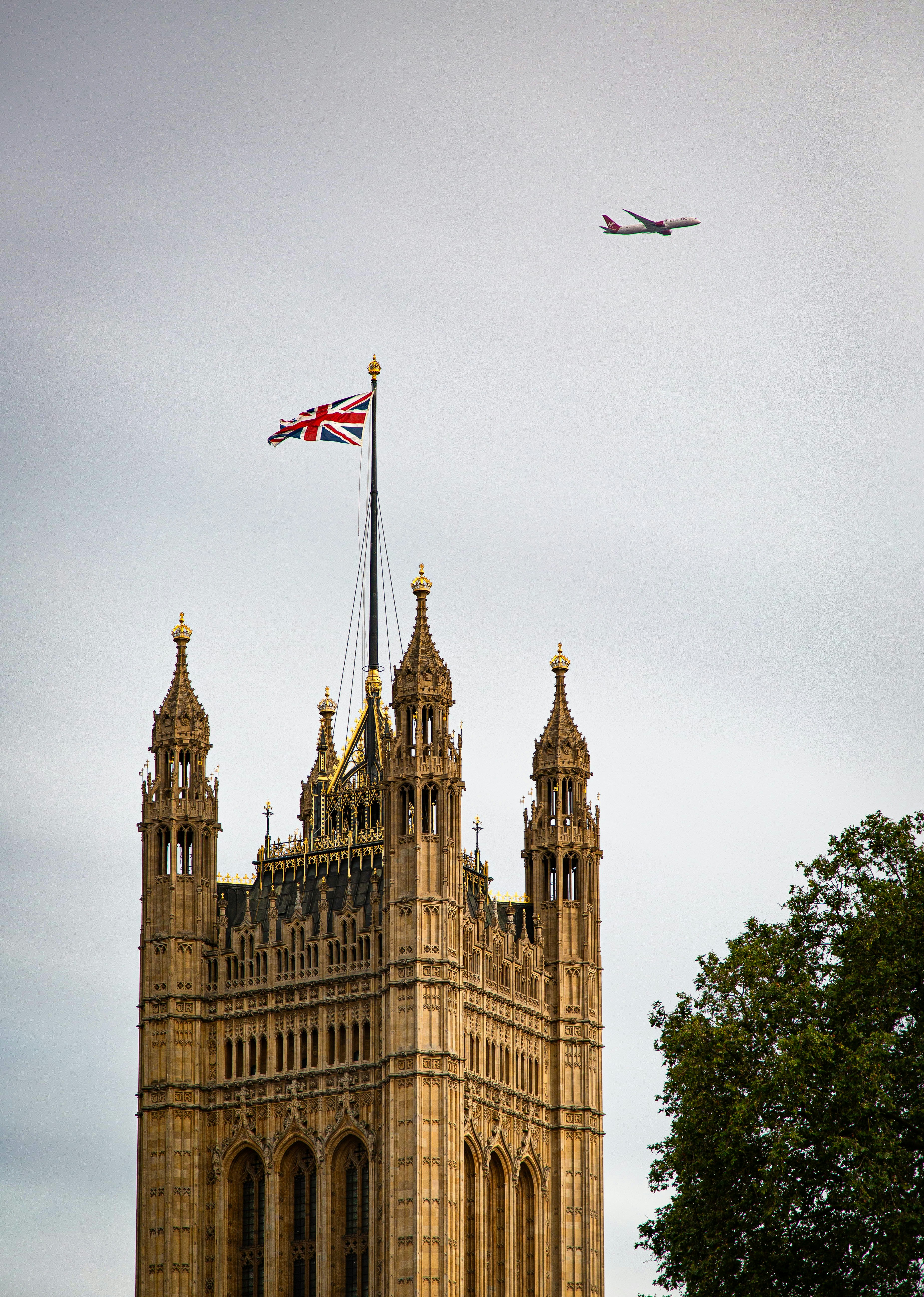 One of the ornate towers of the Palace of Westminster, with a British flag flying above.