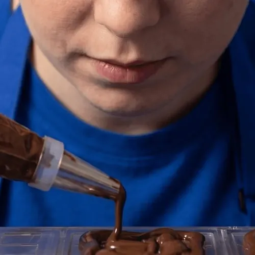 Detail shot of a chef applying chocolate garnish, highlighting precision and artisanal quality. By a branding expert.