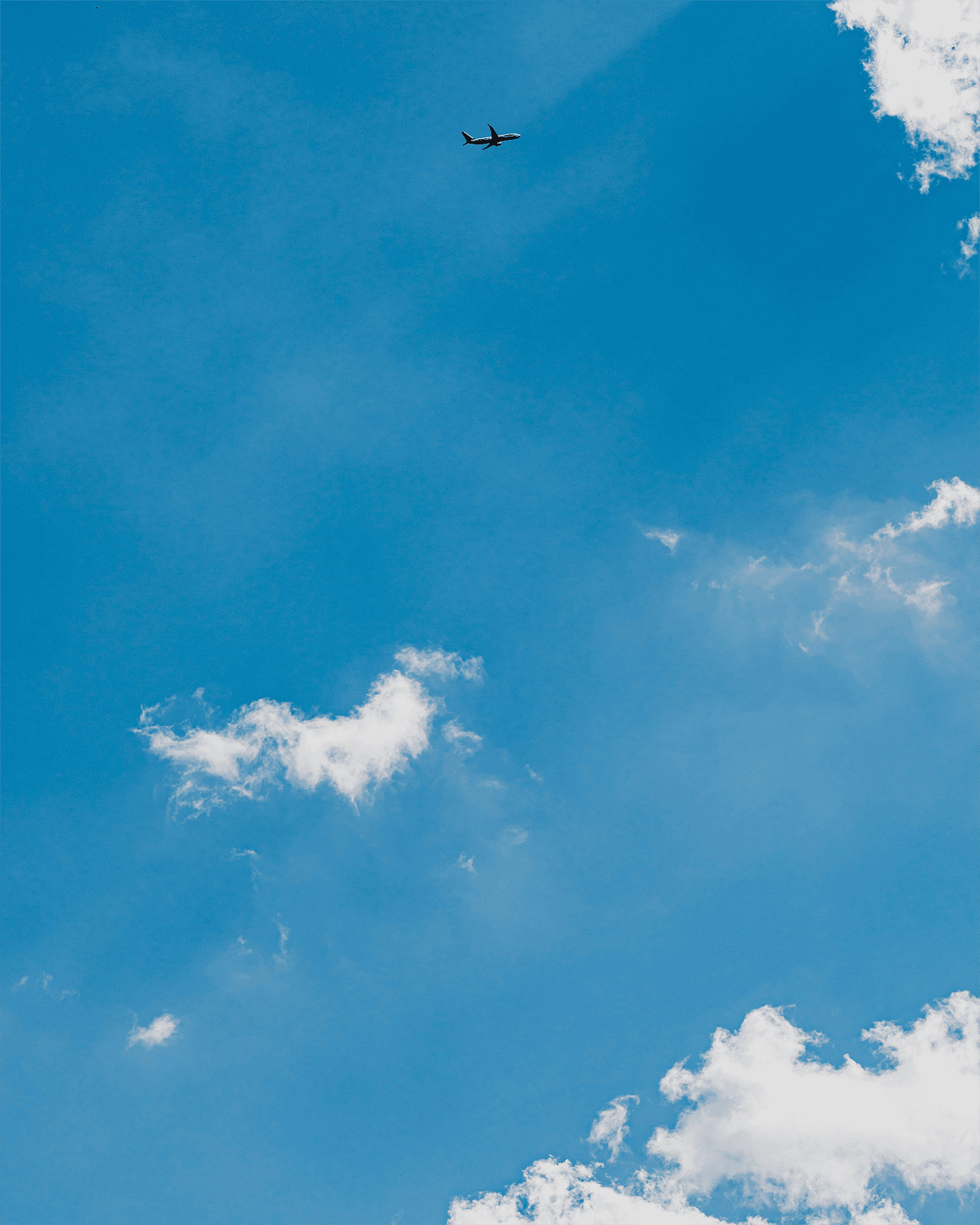 A clear sky with a plane and a cloude on the right.