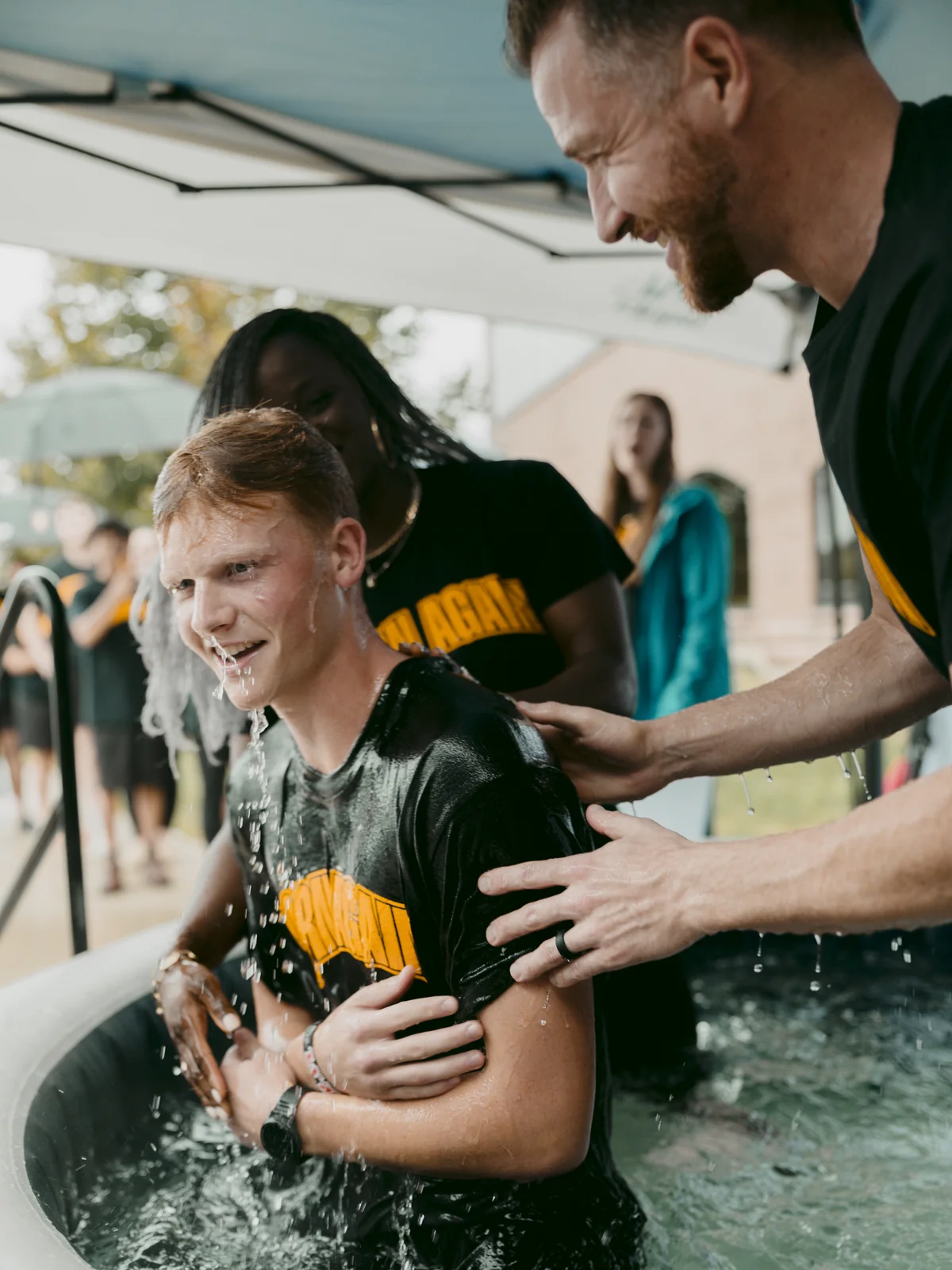 Young man smiling as he comes up from the water at his baptism at Elan Church