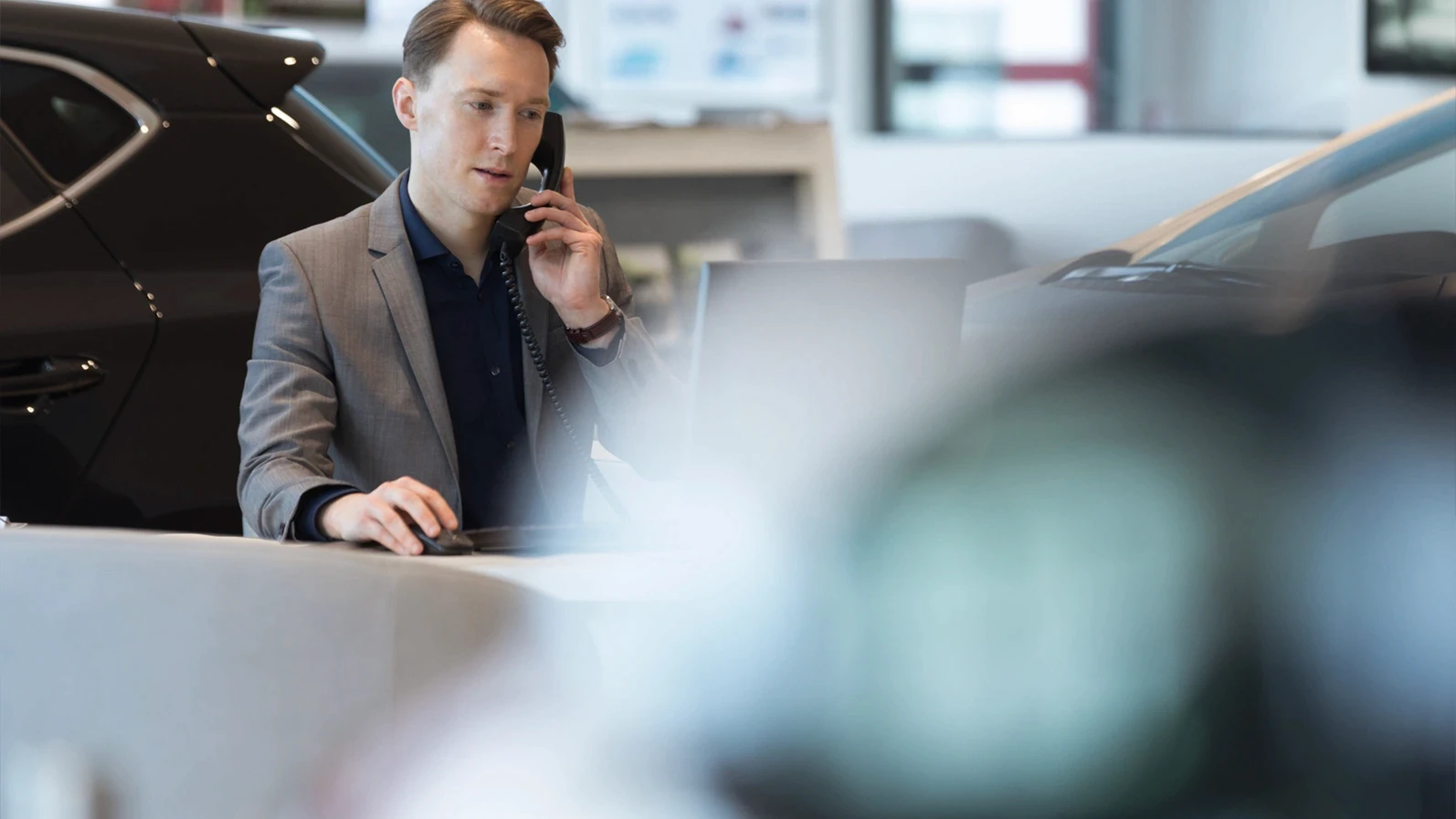 Car salesperson talking on landline phone while working in showroom