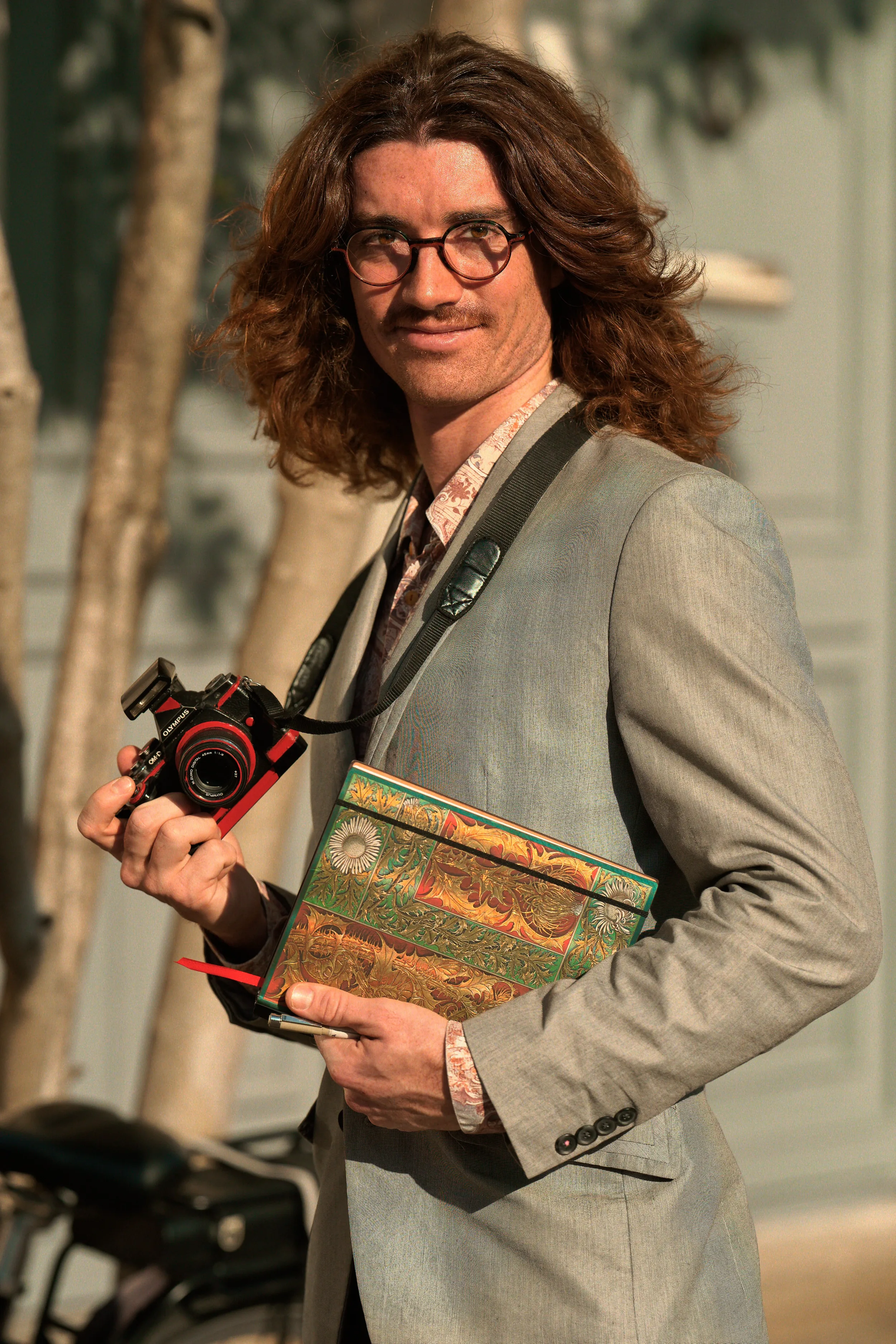 Martin Dedron, un professionnel de la création tenant son appareil photo et son calepin