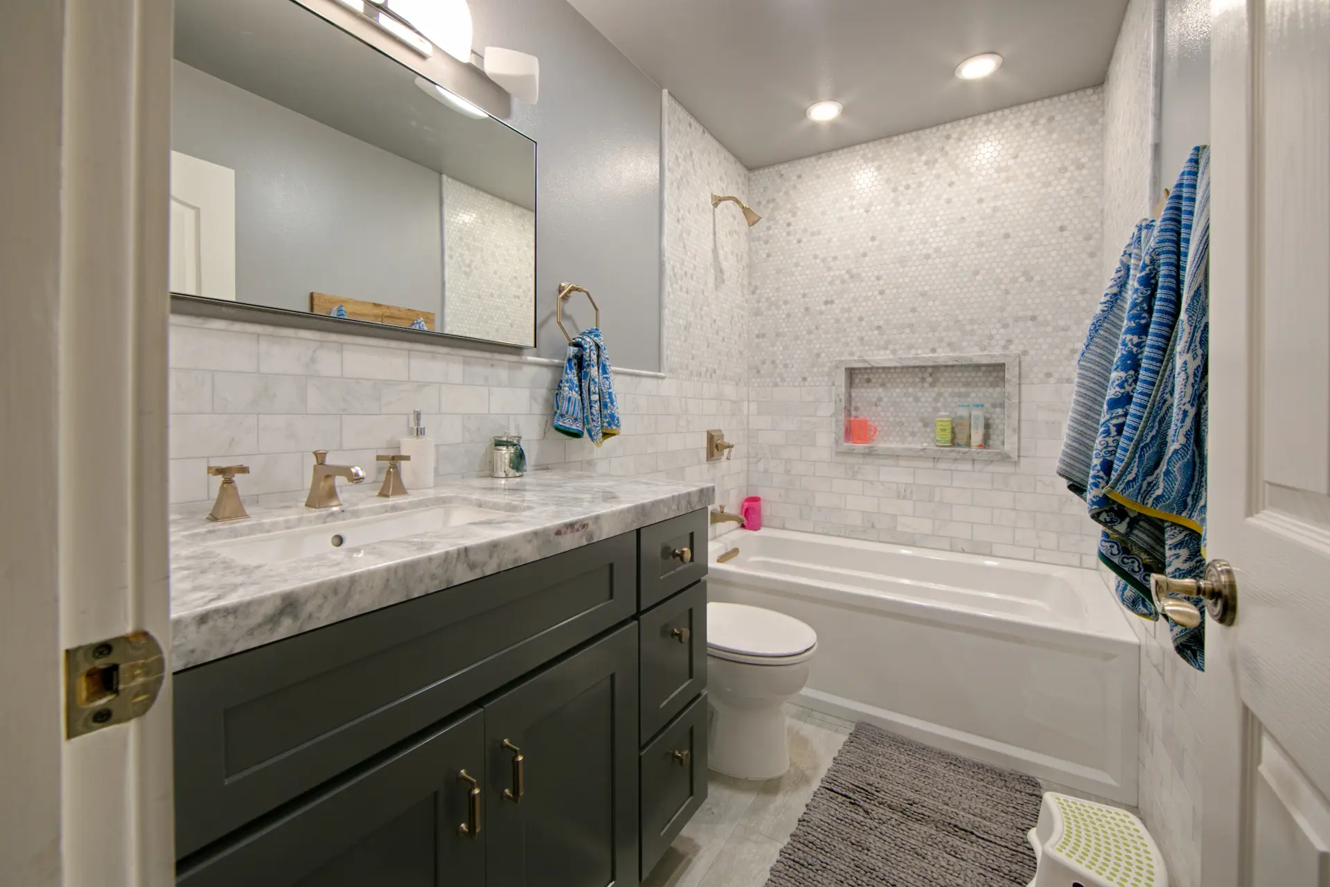 Modern bathroom with dark gray vanity, satin brass fixtures, and white subway tile in Huntington Beach Kitchen & Bath Remodel.