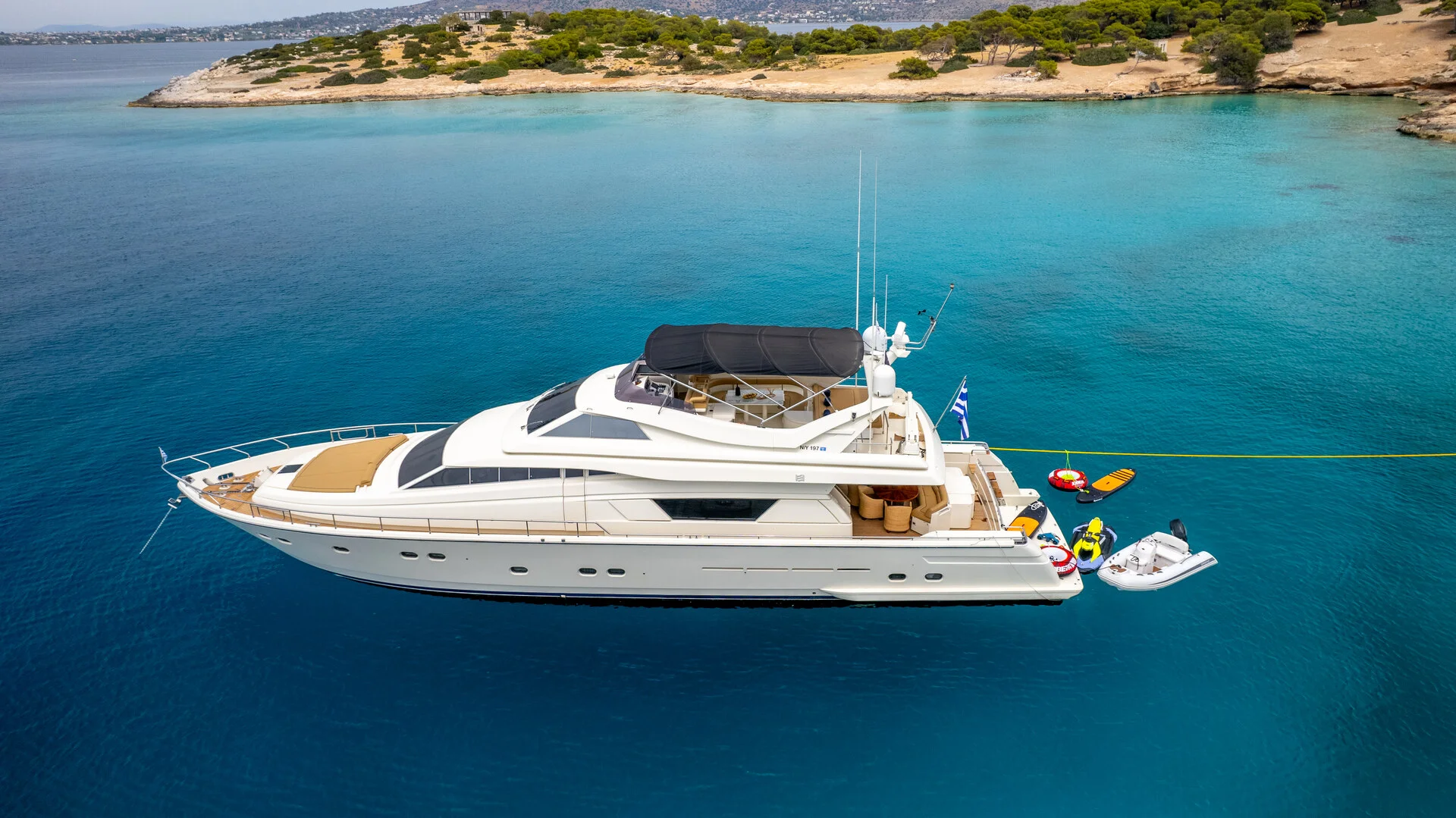 White Rock 36 speedboat with captain at helm cruising calm blue waters near Paros coastline with hills in background.