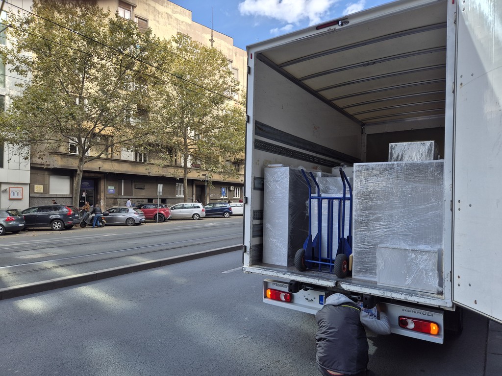 Utovar za selidbe u velikom kombiju, zaštićen nameštaj i transport kolica na ulici.